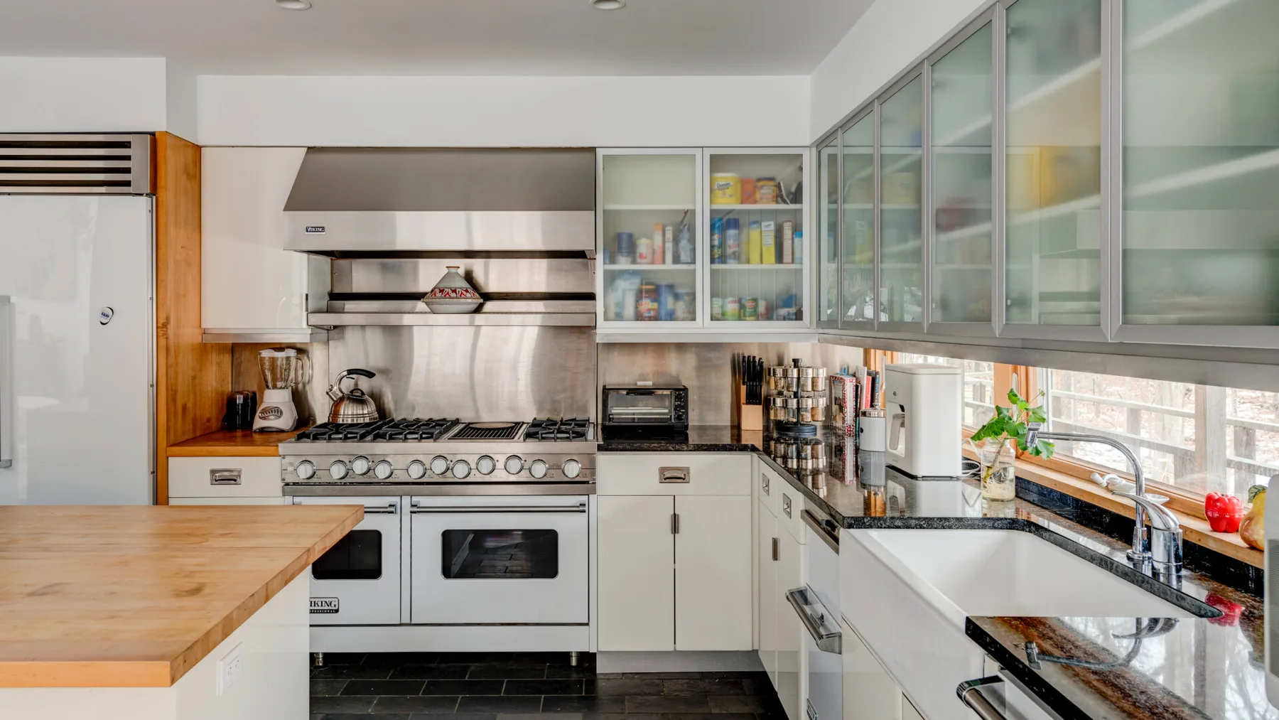 A bright kitchen with a long counter, cooking range, and windows above the sink.