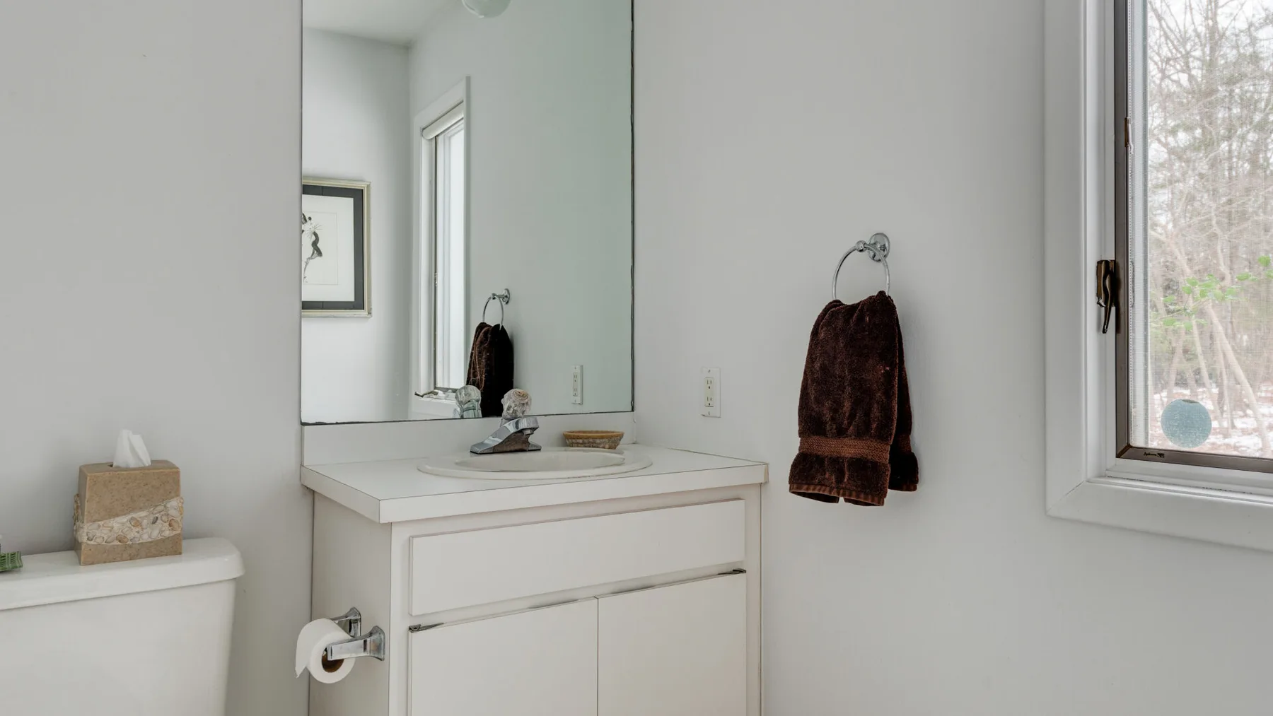 A bright bathroom vanity with a sink and a towel hanging on the wall.