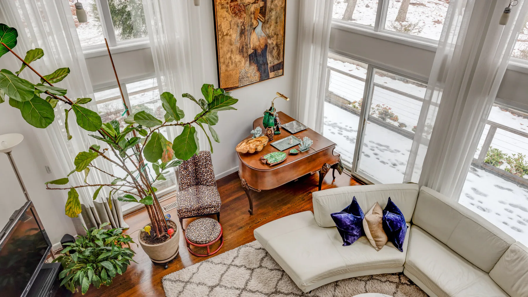 A bright living room with a curved seating area and tall windows.