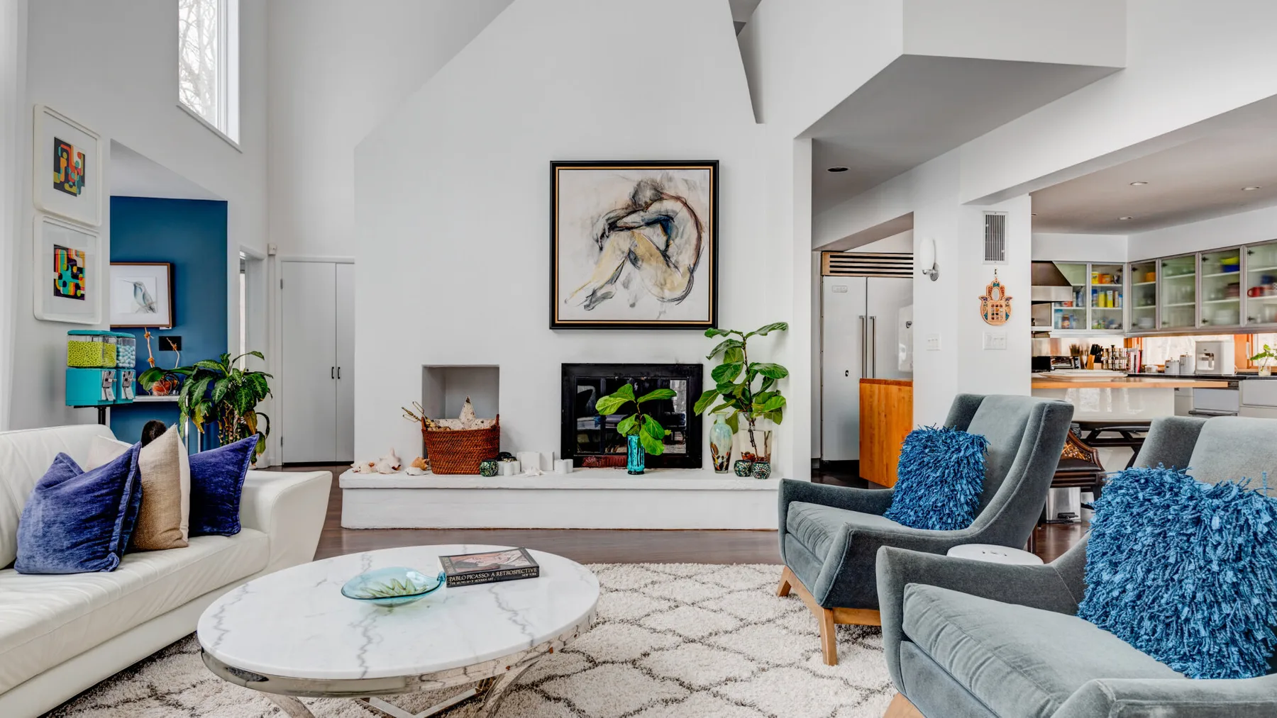 A bright open-plan living room with seating, a coffee table, and a fireplace.