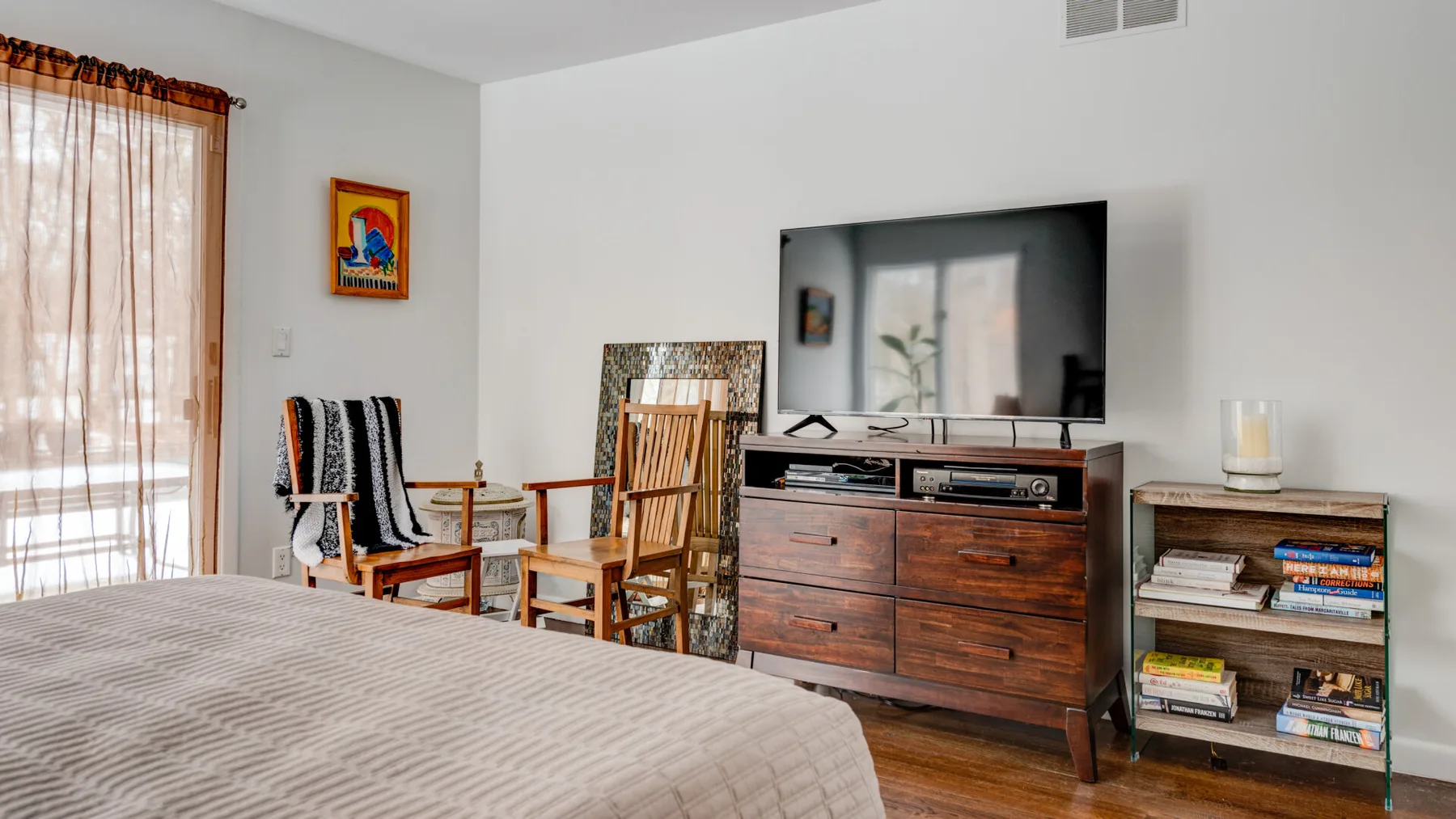 A bedroom with a bed, wooden seating, and a television on a dresser.