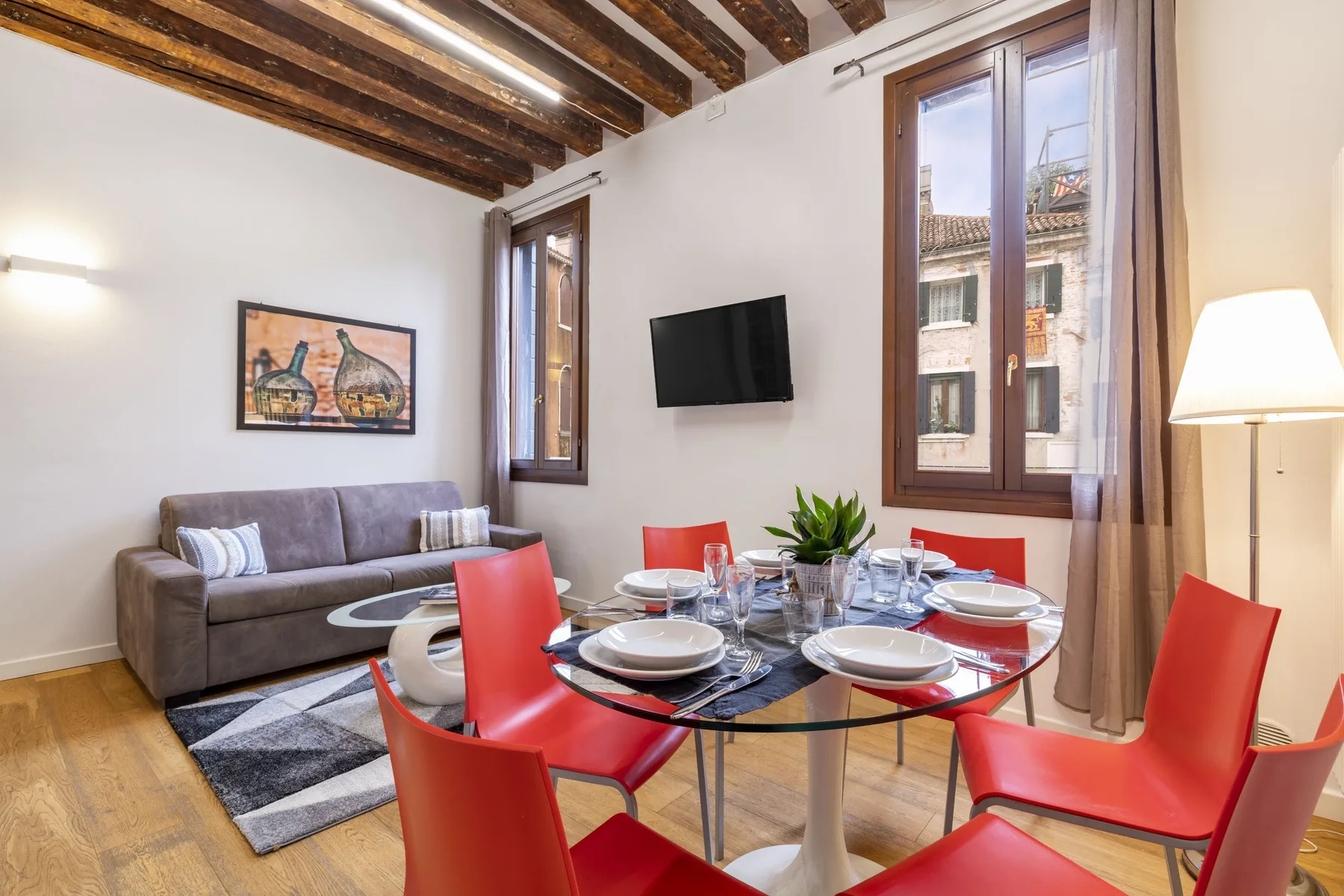 A dining area with a set table and red chairs beside a sofa.