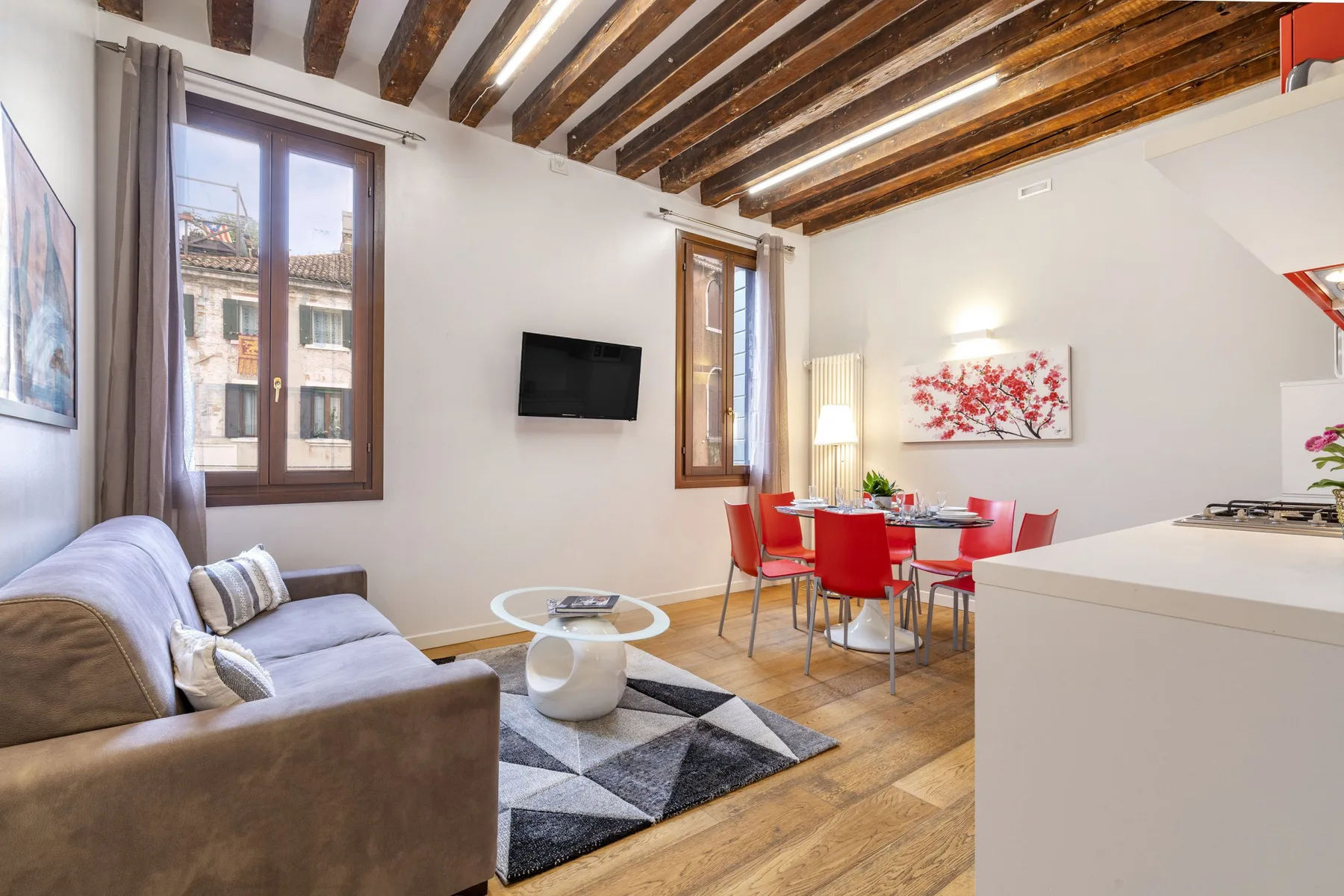 A bright living and dining area with seating, a table, and an open kitchen.