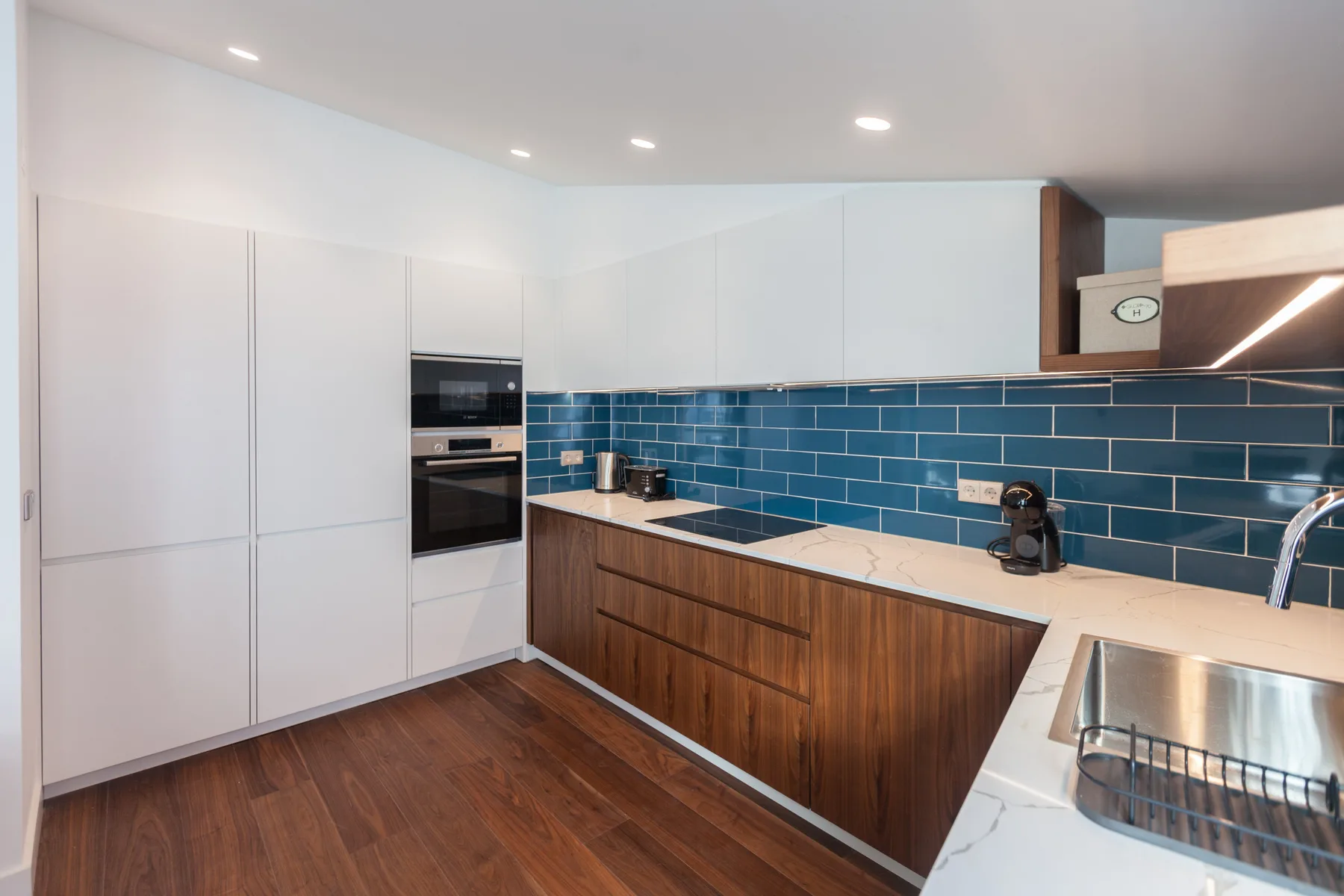 Una cocina moderna con paredes de azulejos azules y armarios de madera.
