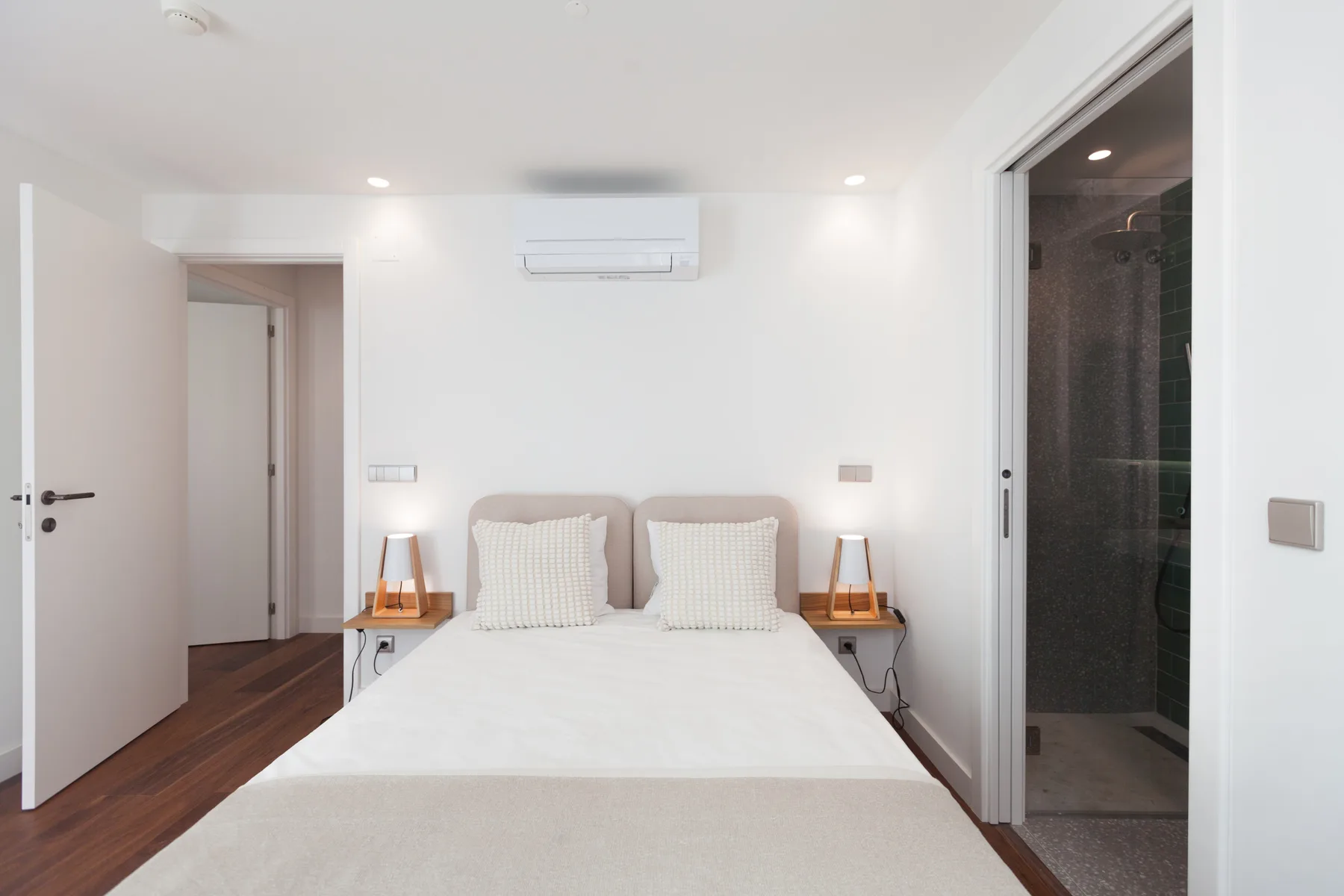 Un dormitorio luminoso con una cama doble y una puerta abierta a un baño.