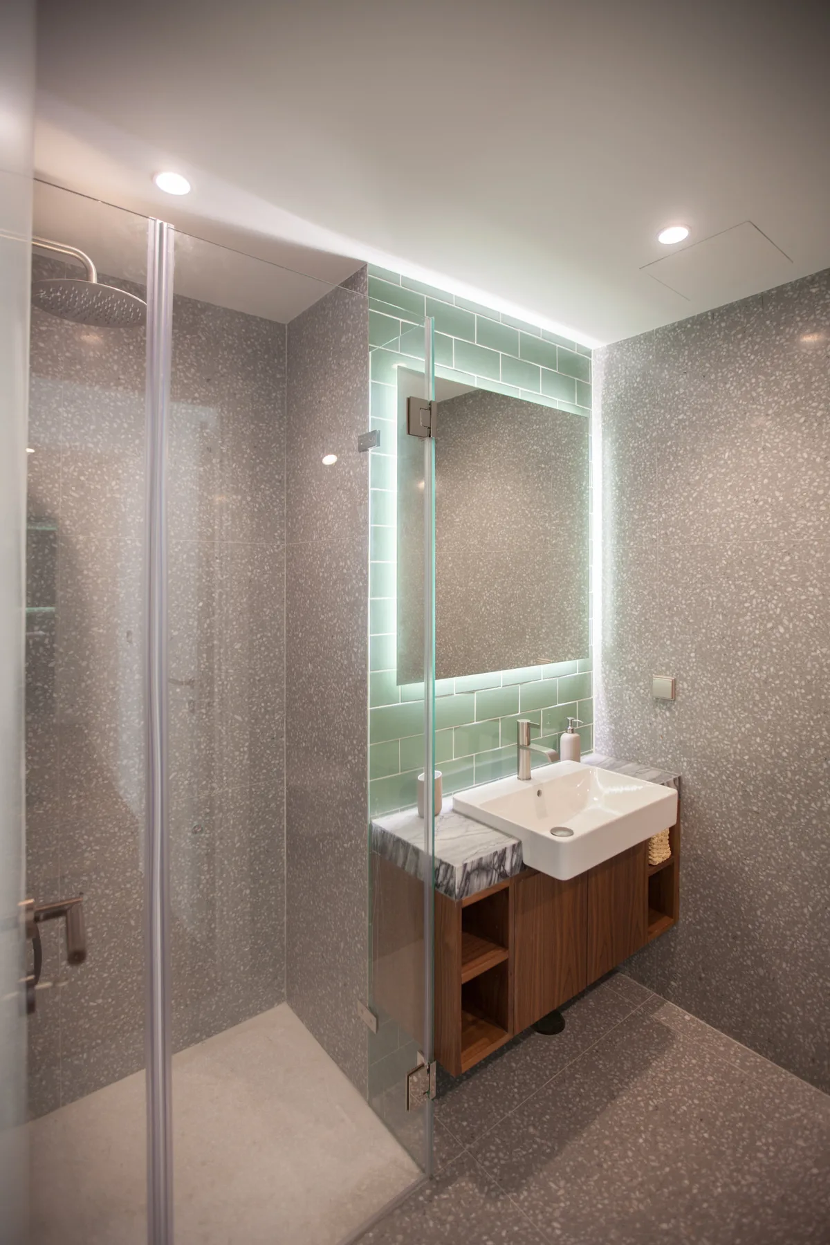 Un baño con ducha acristalada y un lavabo con mueble.
