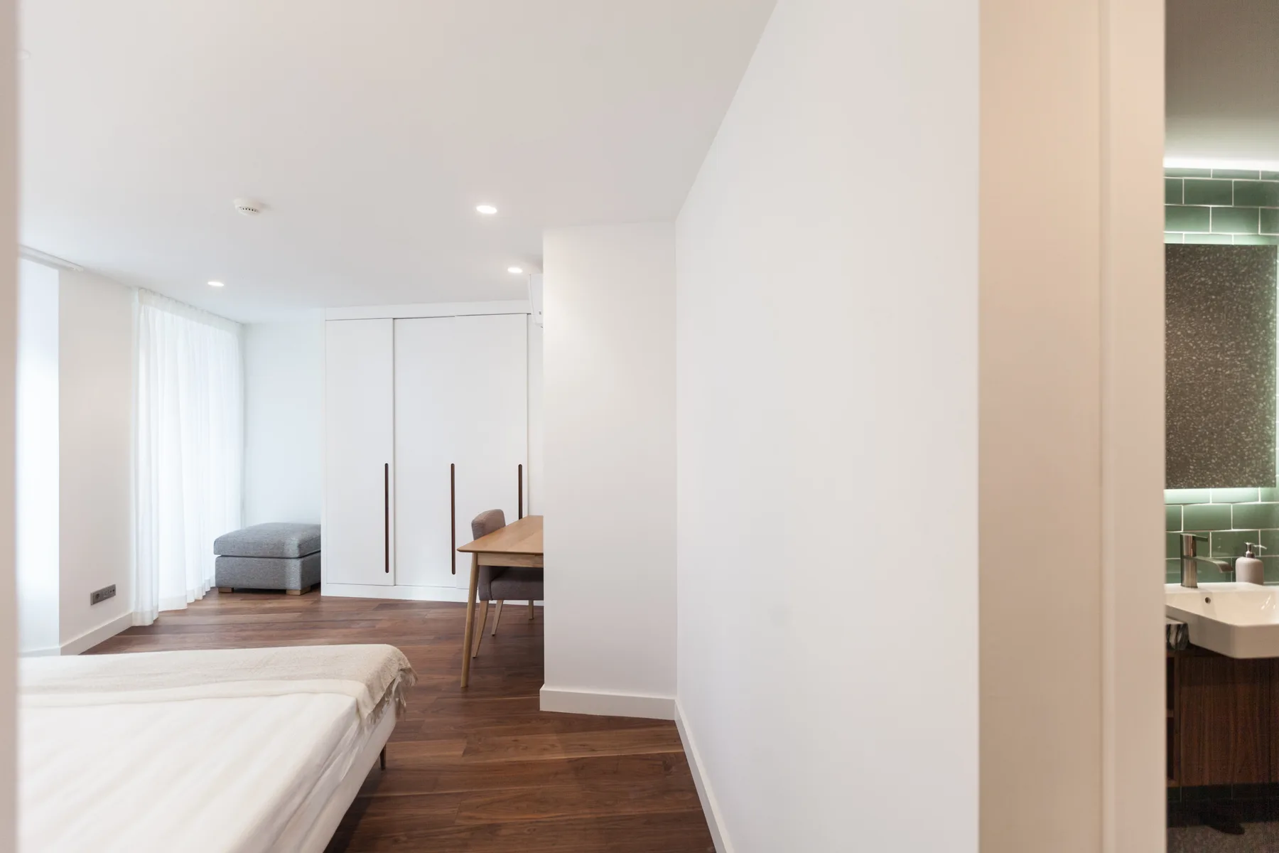 A bright bedroom opens into a small sitting area and a bathroom.