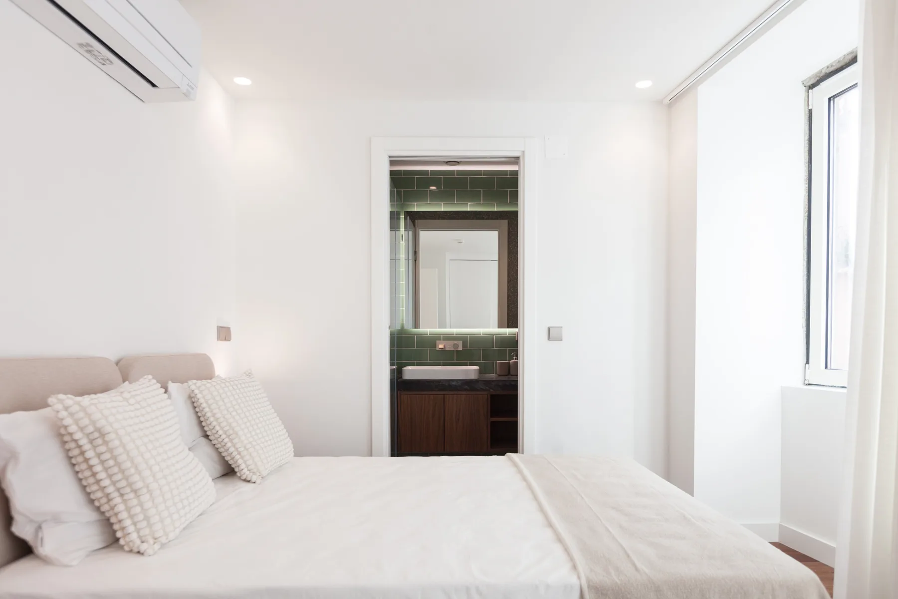 Un dormitorio luminoso con una cama y una puerta abierta al baño.