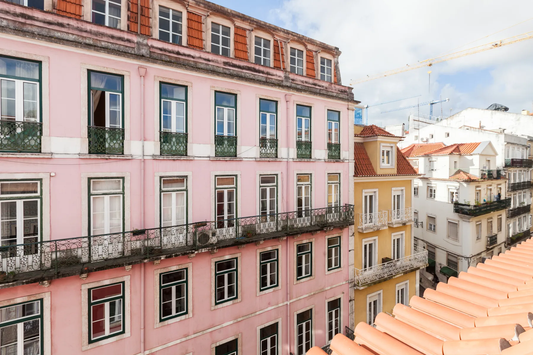 Edificios rosados de varias plantas con balcones dan a tejados cercanos.