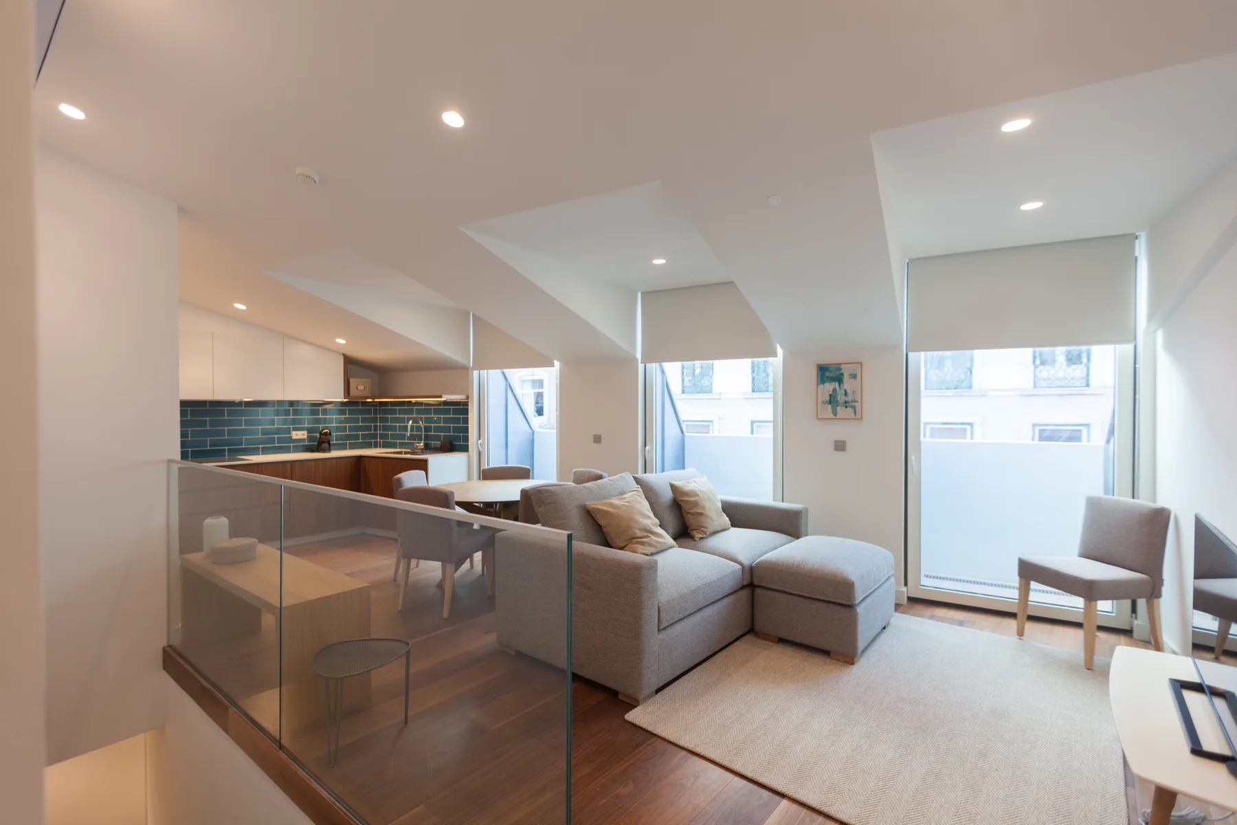 Sala de estar de concepto abierto con asientos junto a una cocina y grandes ventanas.