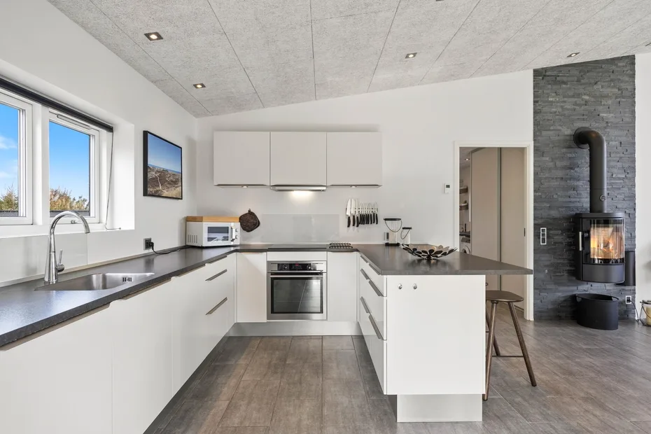 Una cocina moderna con armarios blancos, encimeras oscuras y una isla.