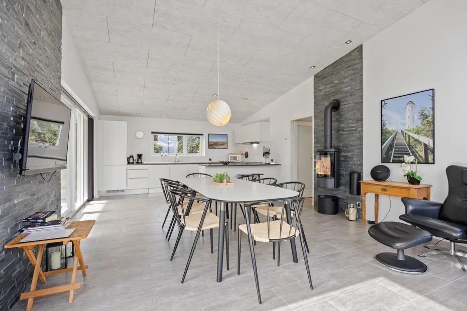 Un comedor y cocina modernos de concepto abierto, con una mesa larga y asientos.