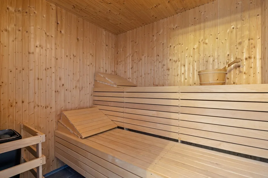 Una sauna revestida de madera, con bancos escalonados y un cubo sobre el banco superior.