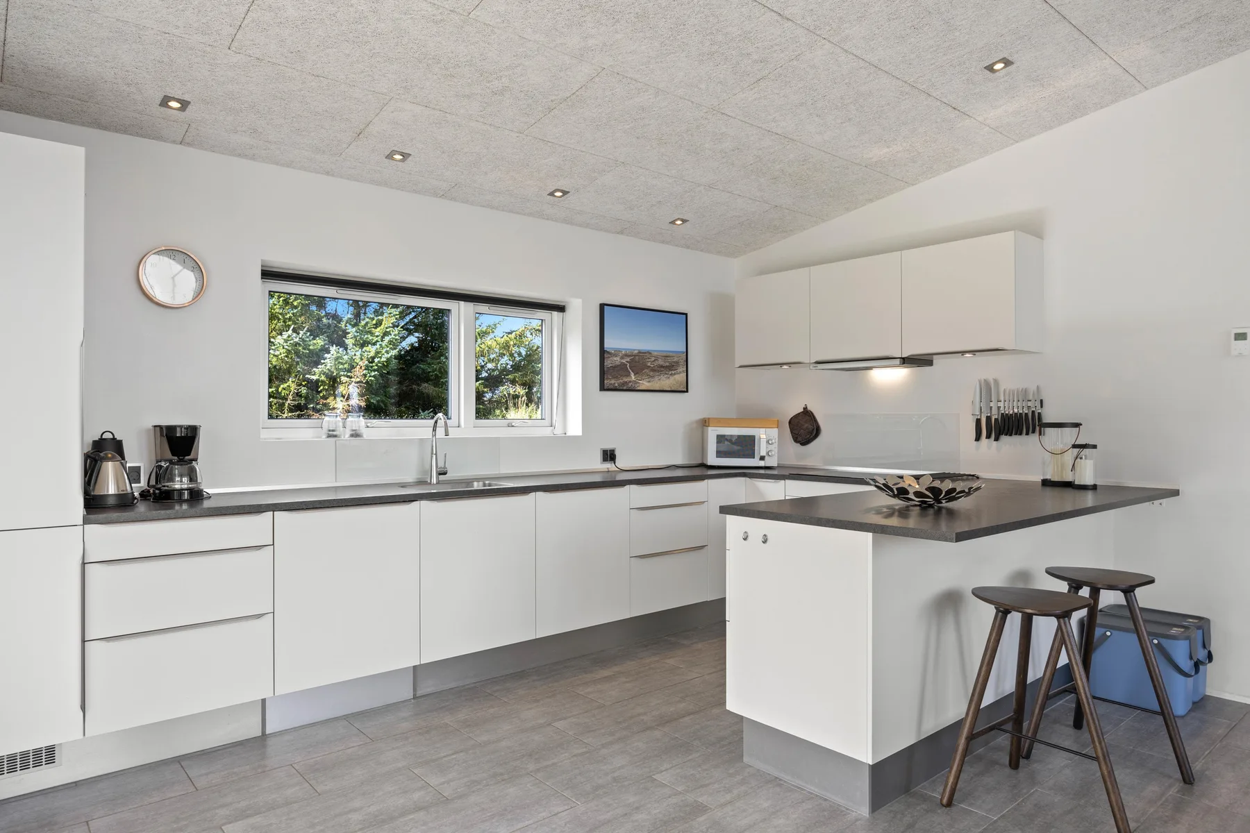 Una cocina luminosa con gabinetes blancos y una isla central.