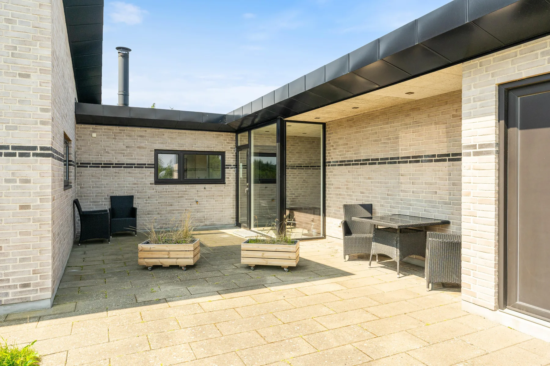 Un patio pavimentado con asientos y una mesa al lado de la casa.