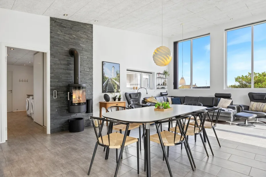 Una luminosa sala de estar y comedor de concepto abierto, con una mesa larga y grandes ventanas.