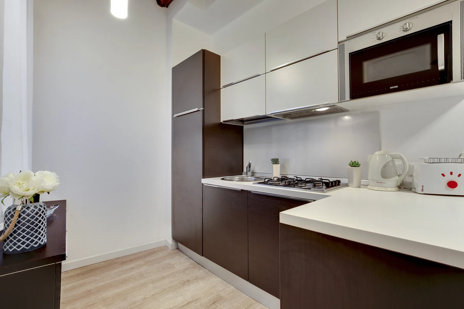 A modern kitchen with dark cabinetry, a cooktop, and a white counter.