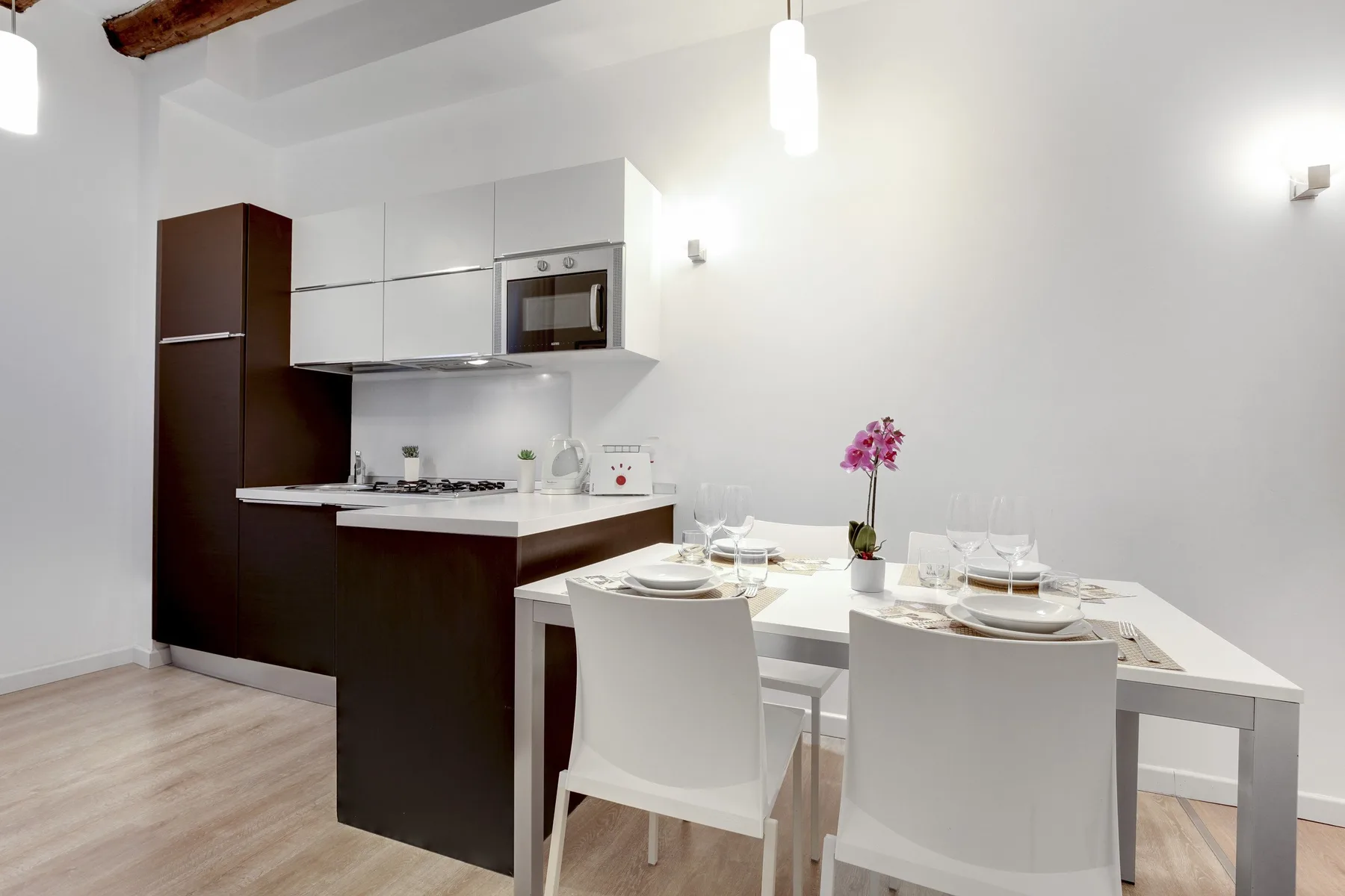 A bright kitchen and dining area with white cabinetry and a set table.