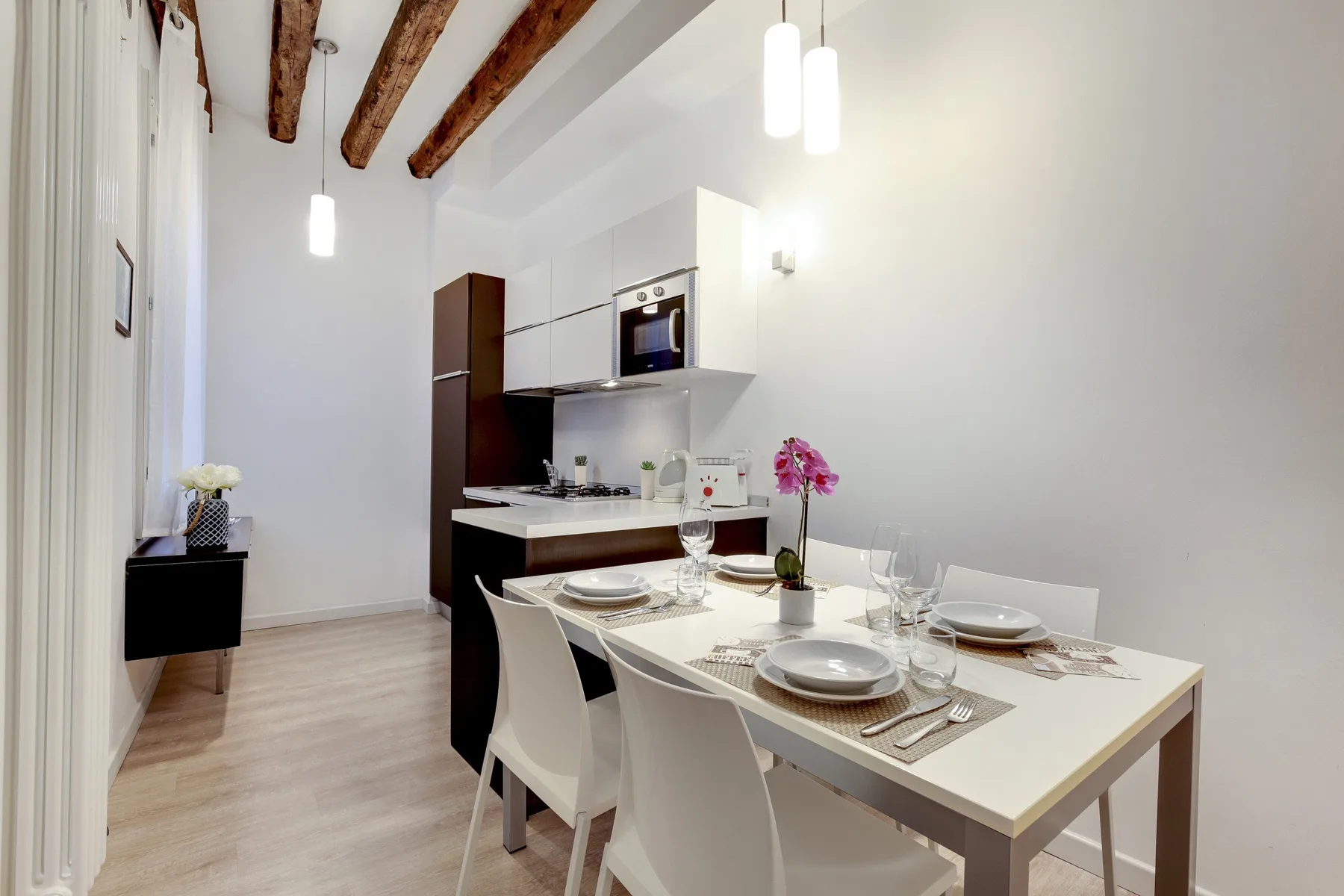 A dining area with a set table beside a compact kitchen.