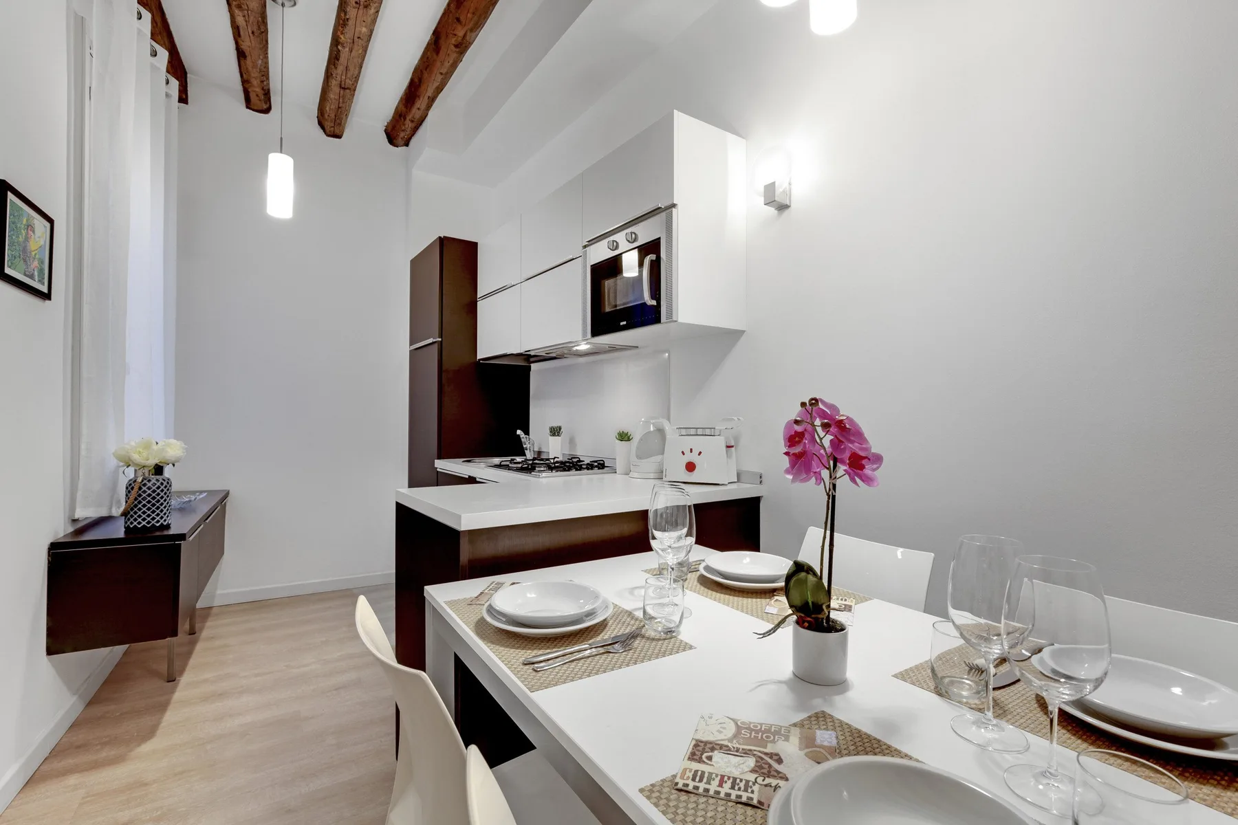 A bright dining area with a set table beside a compact kitchen.