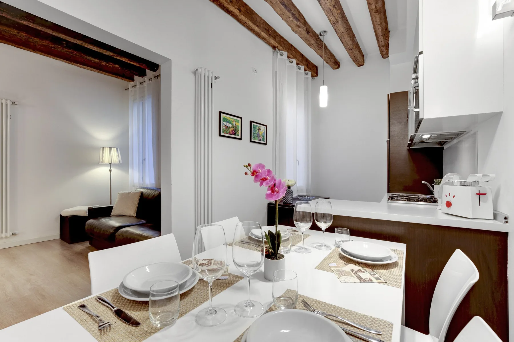 A dining area beside an open kitchen, with a table set for a meal.