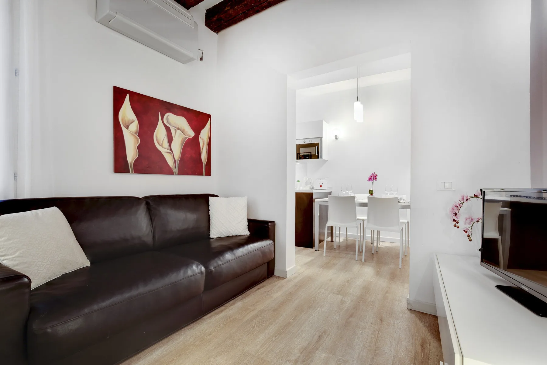 A bright living room with a dark sofa and a dining table in the adjoining space.