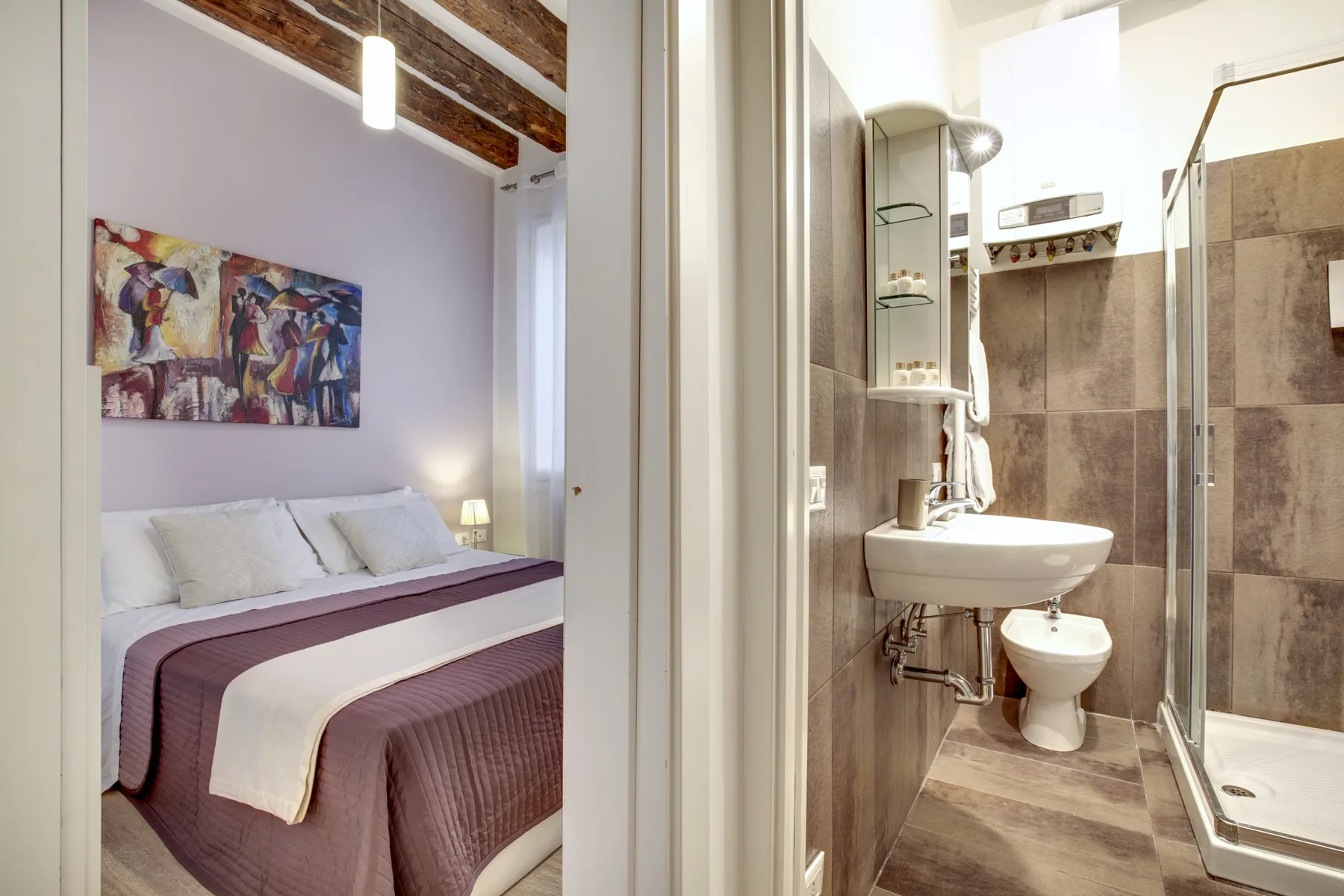 A bedroom with a neatly made bed beside an adjoining bathroom.