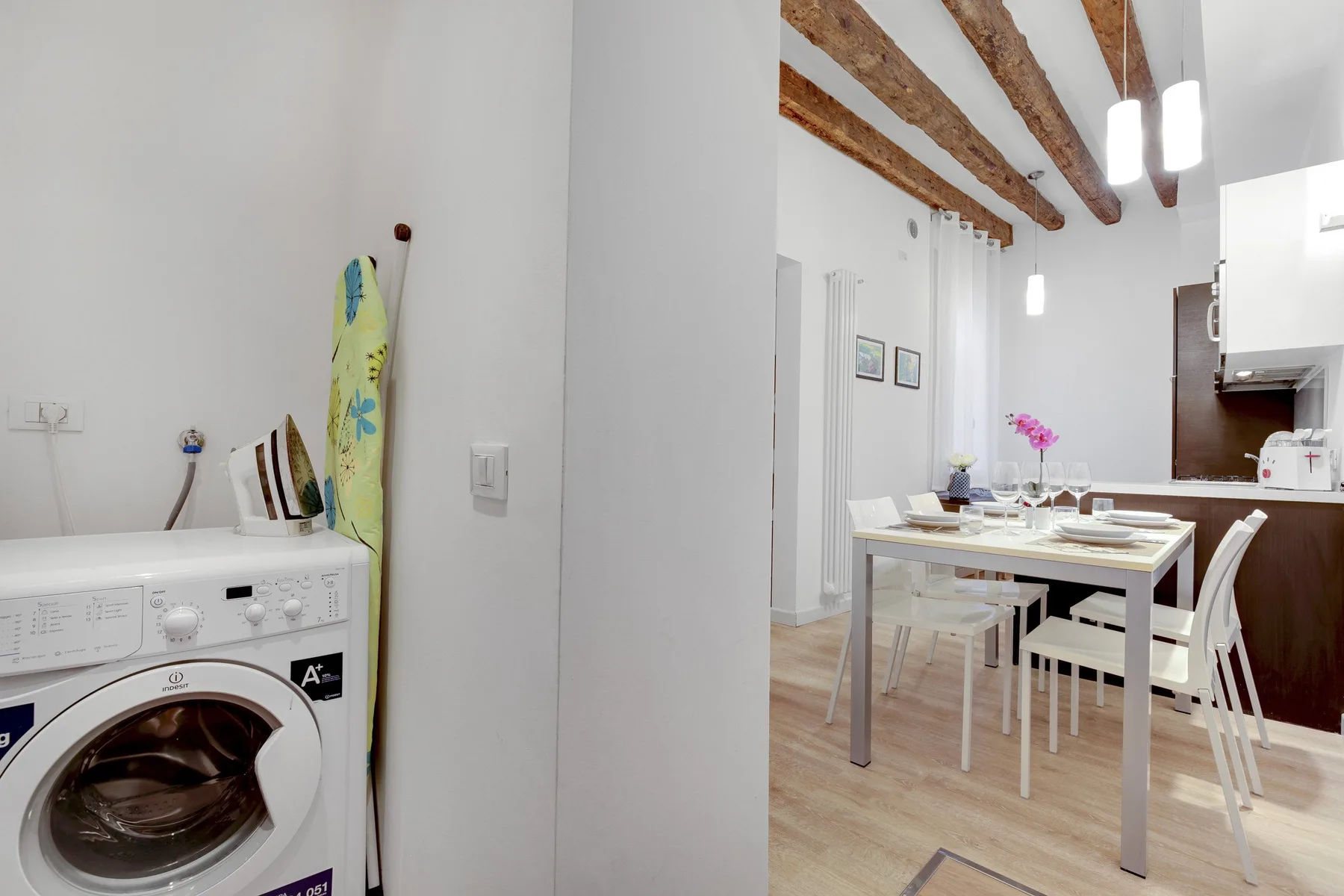 A dining area with a set table beside a compact kitchen.