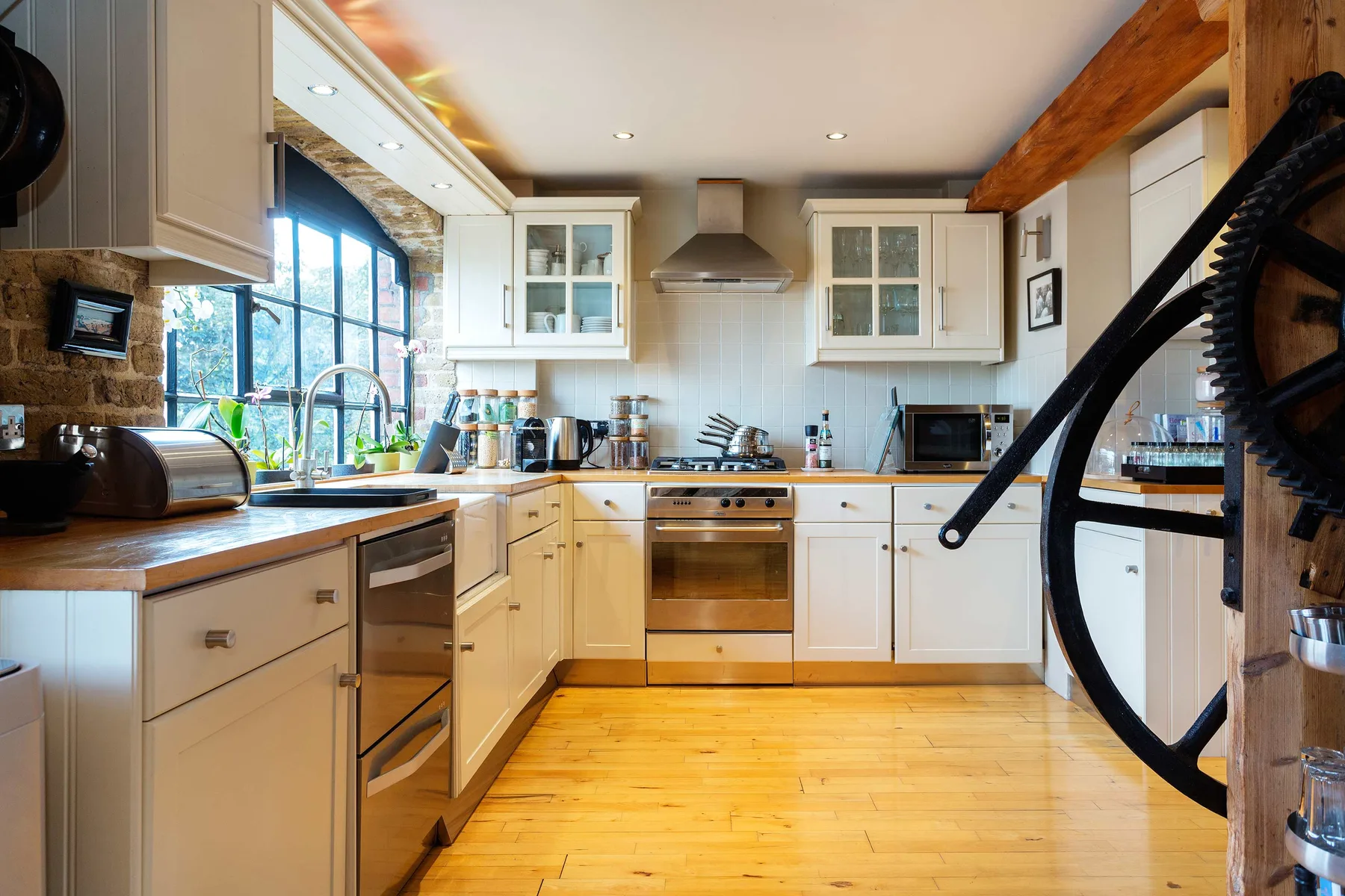 A bright kitchen with white cabinets, wooden countertops, and a central cooking area.