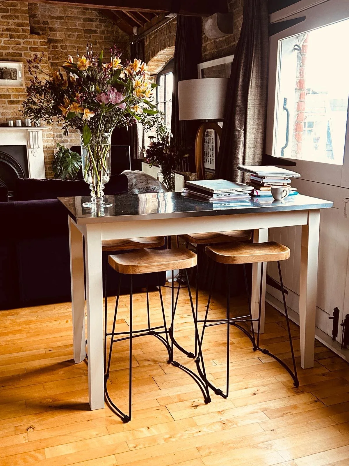 A bright dining area has a table with stools beside a large window.