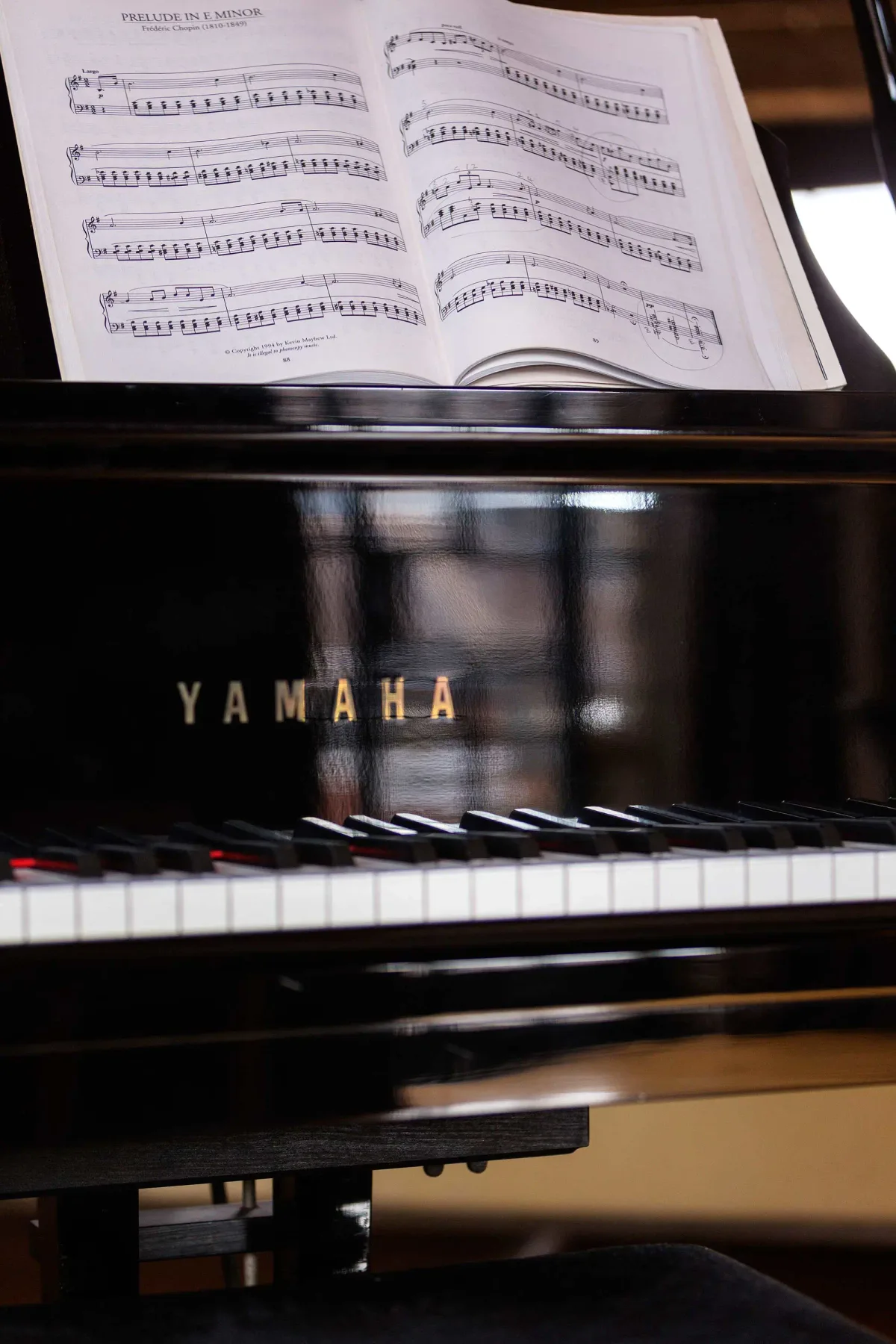 A piano with an open book of sheet music on its music stand.