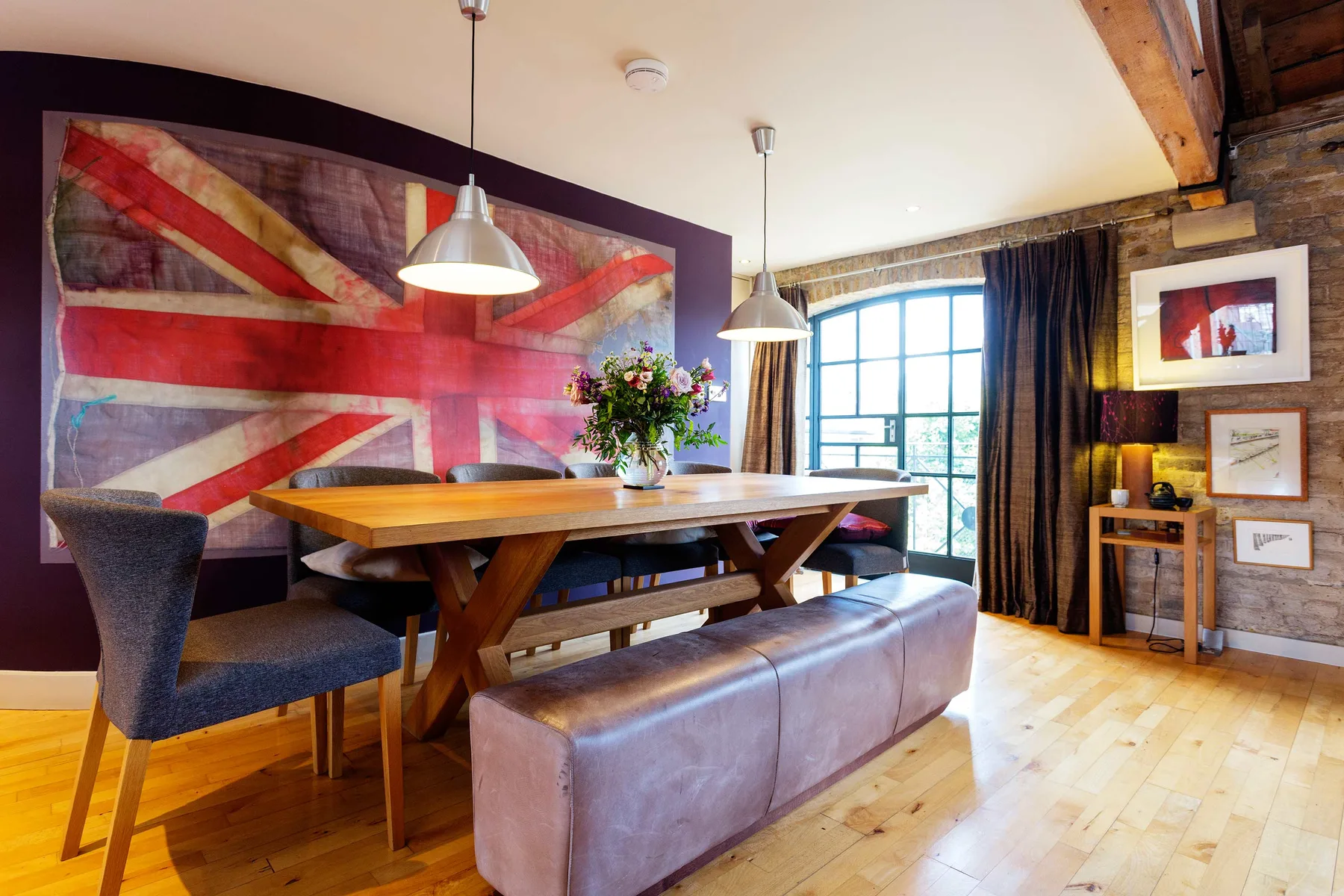 A dining area with a wooden table, bench seating, and a large wall mural.