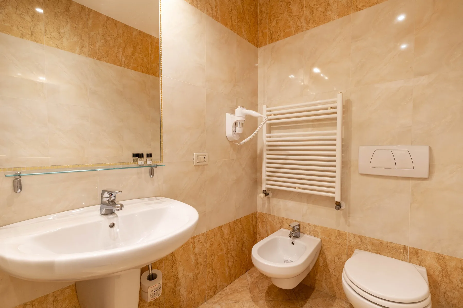 A bathroom with a sink, toilet, and wall-mounted towel warmer.