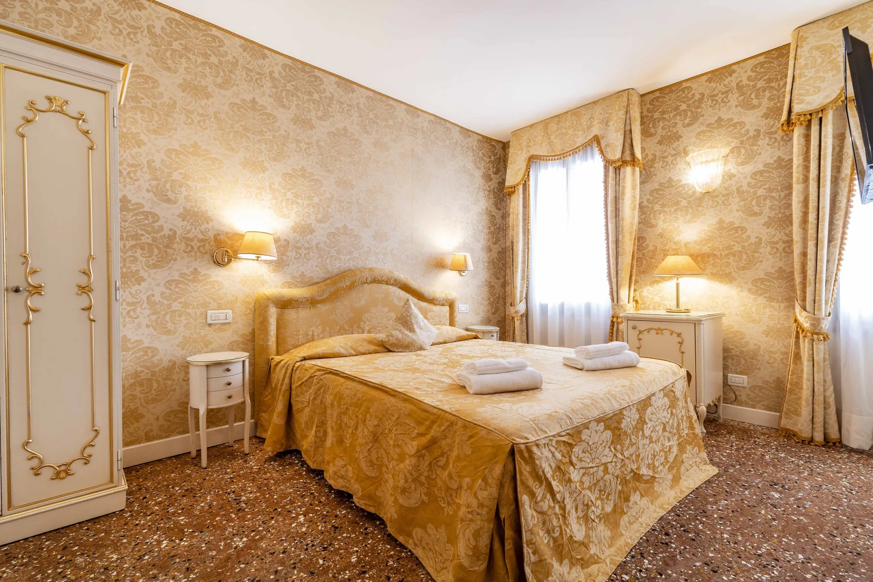 A bedroom with a double bed, bedside tables, and a curtained window.