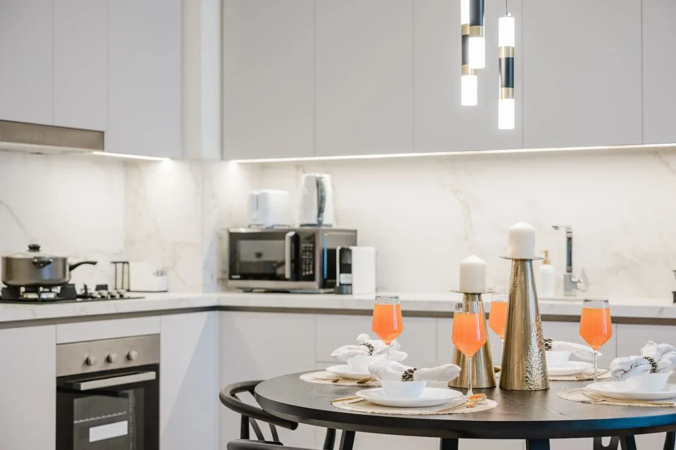 Cocina y comedor modernos con una mesa puesta y armarios blancos.