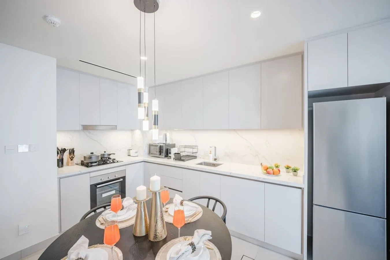 Una cocina moderna y luminosa con gabinetes blancos y una mesa de comedor en primer plano.