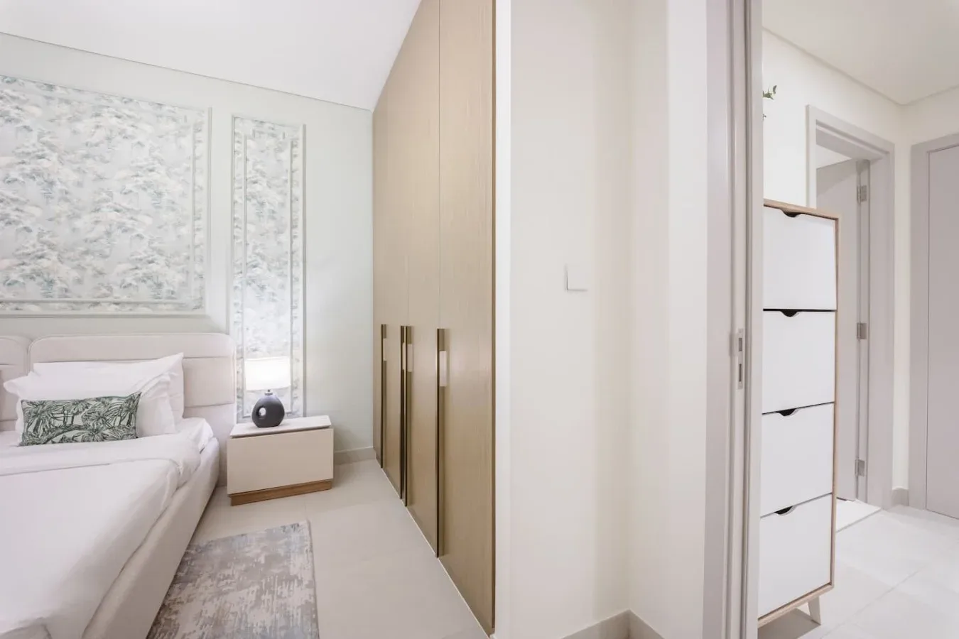 Un dormitorio luminoso con una cama, una mesita de noche y armarios empotrados.