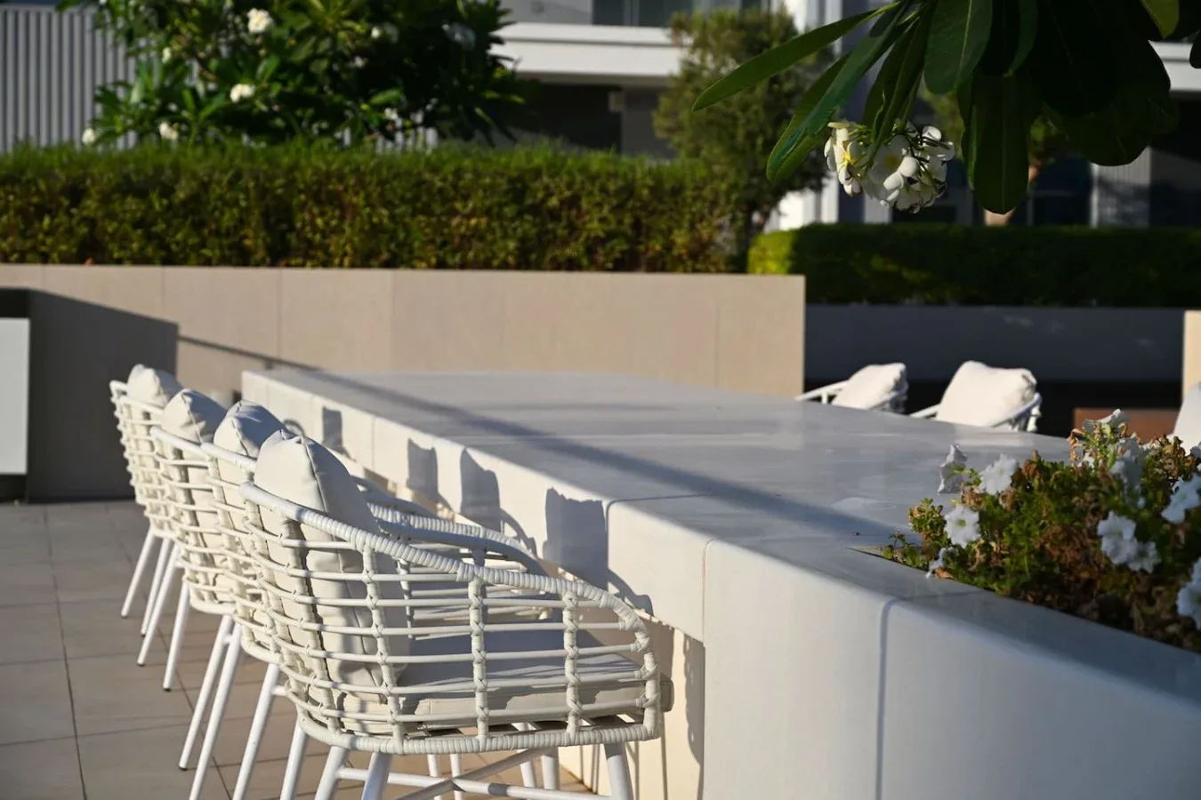 Un patio al aire libre con asientos blancos junto a una barra larga.