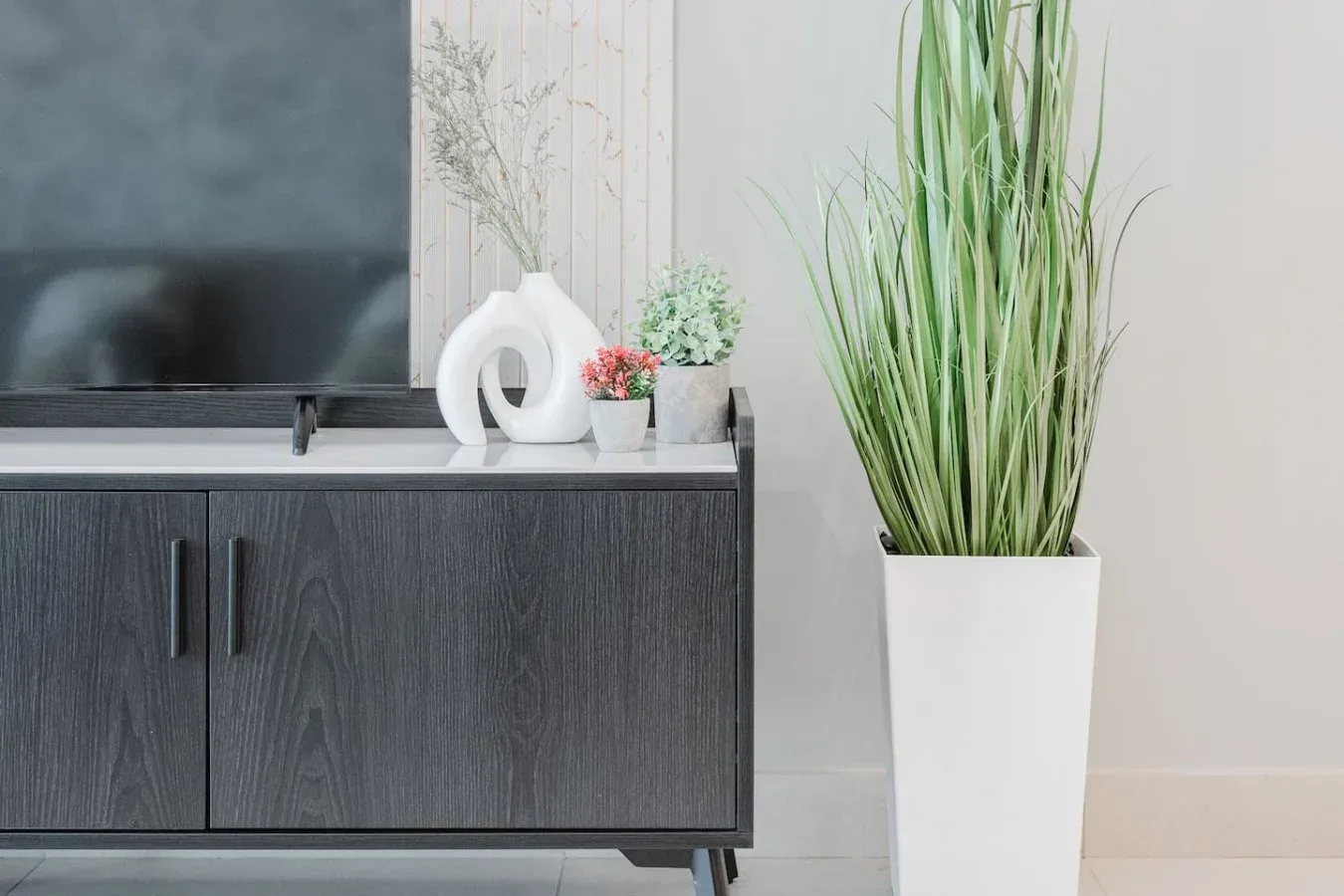 Un mueble para televisor está junto a una planta alta en maceta.