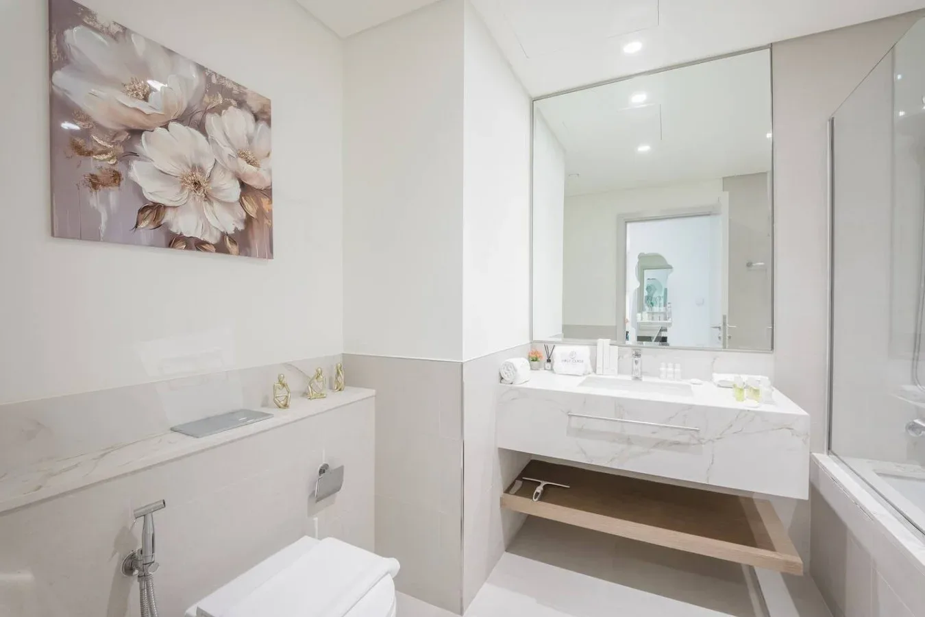 Un baño luminoso con un amplio tocador, un espejo grande y una bañera.