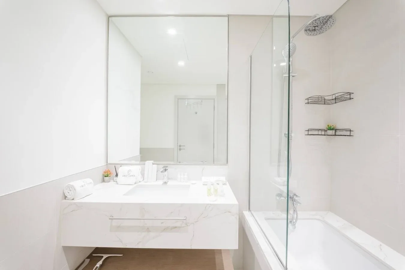Un baño luminoso con un amplio tocador y una ducha con mampara de vidrio.
