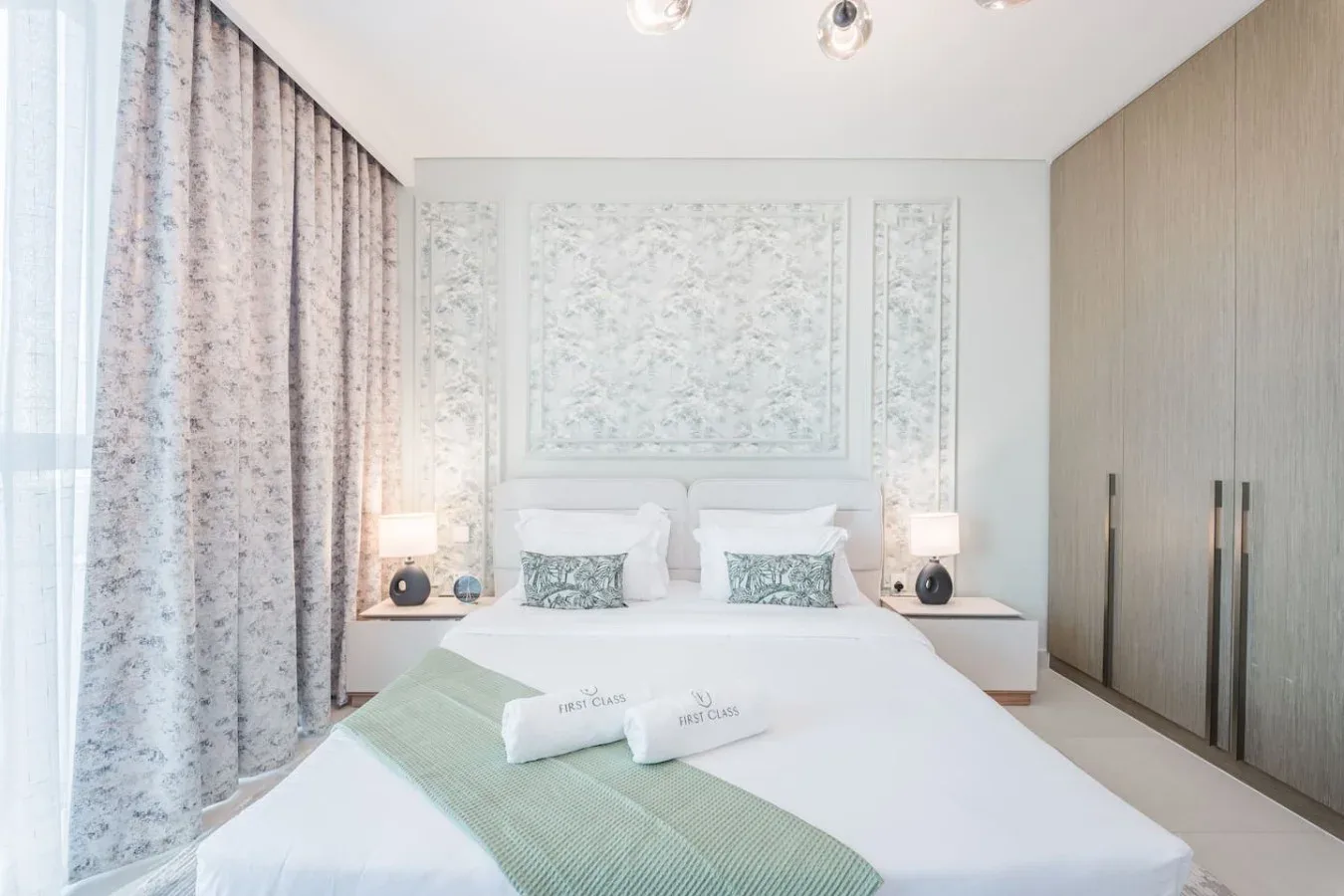 Un dormitorio luminoso con una cama bien hecha y cortinas estampadas.