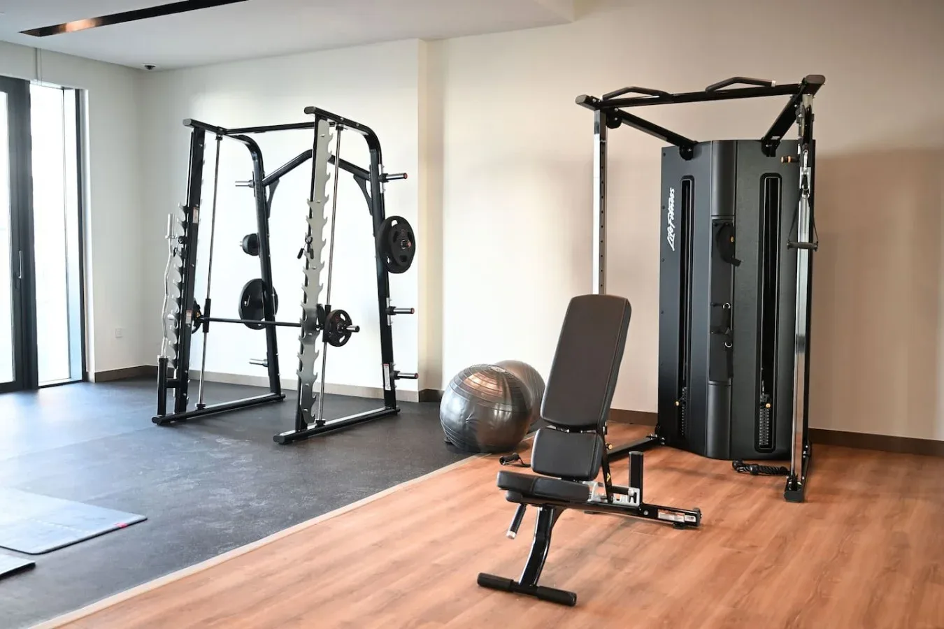 Un gimnasio con máquinas de pesas, un banco de ejercicios y una pelota de ejercicio.