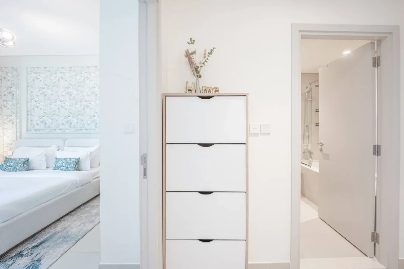 Un dormitorio luminoso con una cama junto a una cómoda blanca.