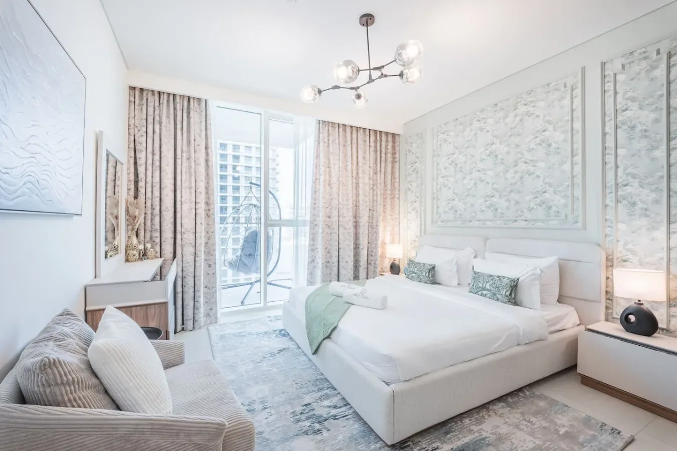 Un dormitorio luminoso con una cama grande y puertas de vidrio que dan a un balcón.