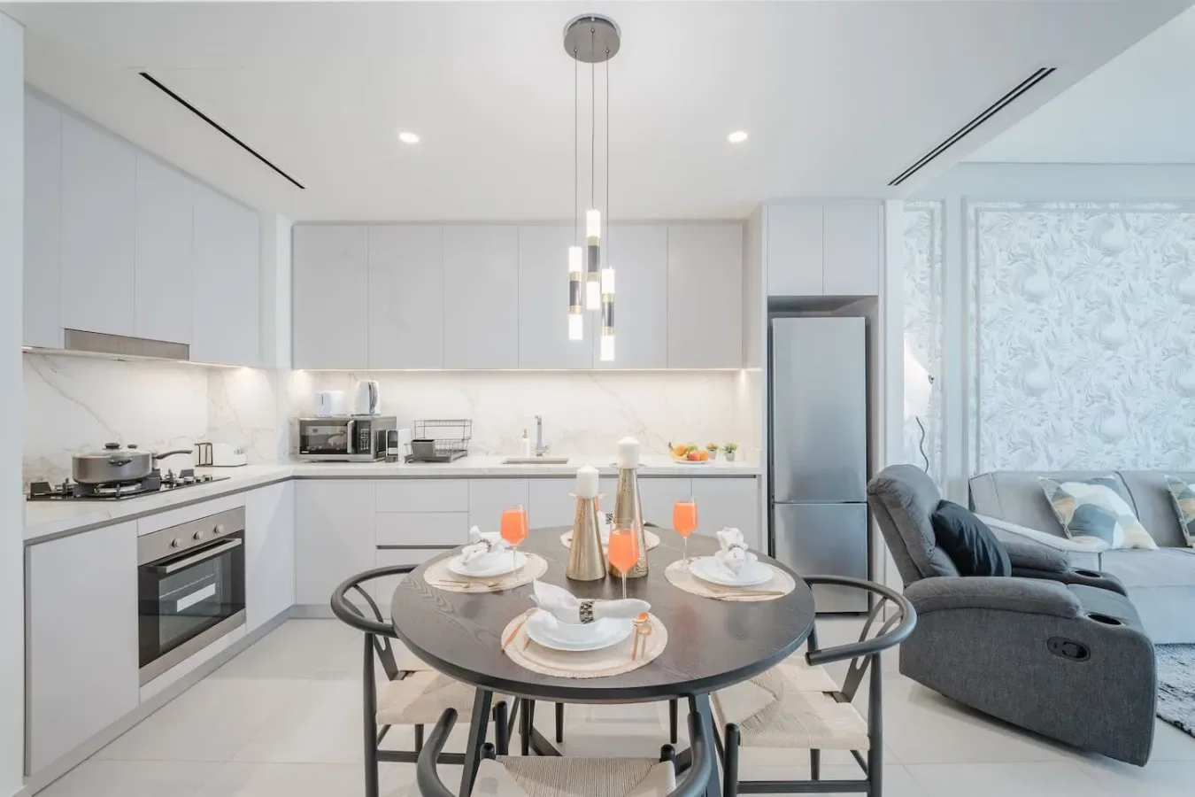 Una cocina y comedor modernos y luminosos, con una mesa redonda y asientos grises.