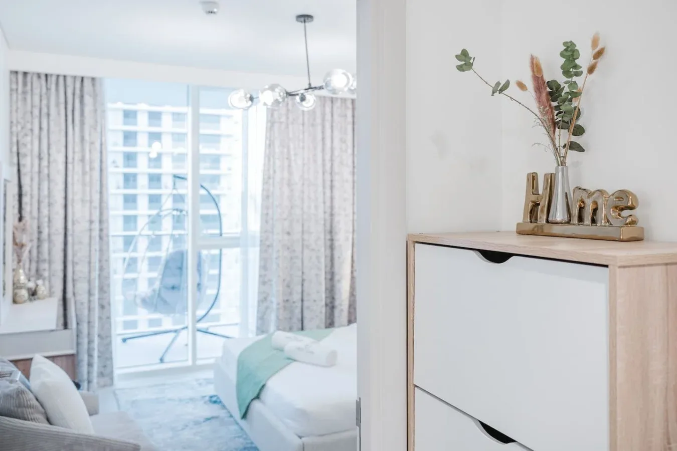 Un dormitorio luminoso con una cama junto a una puerta de vidrio y cortinas.