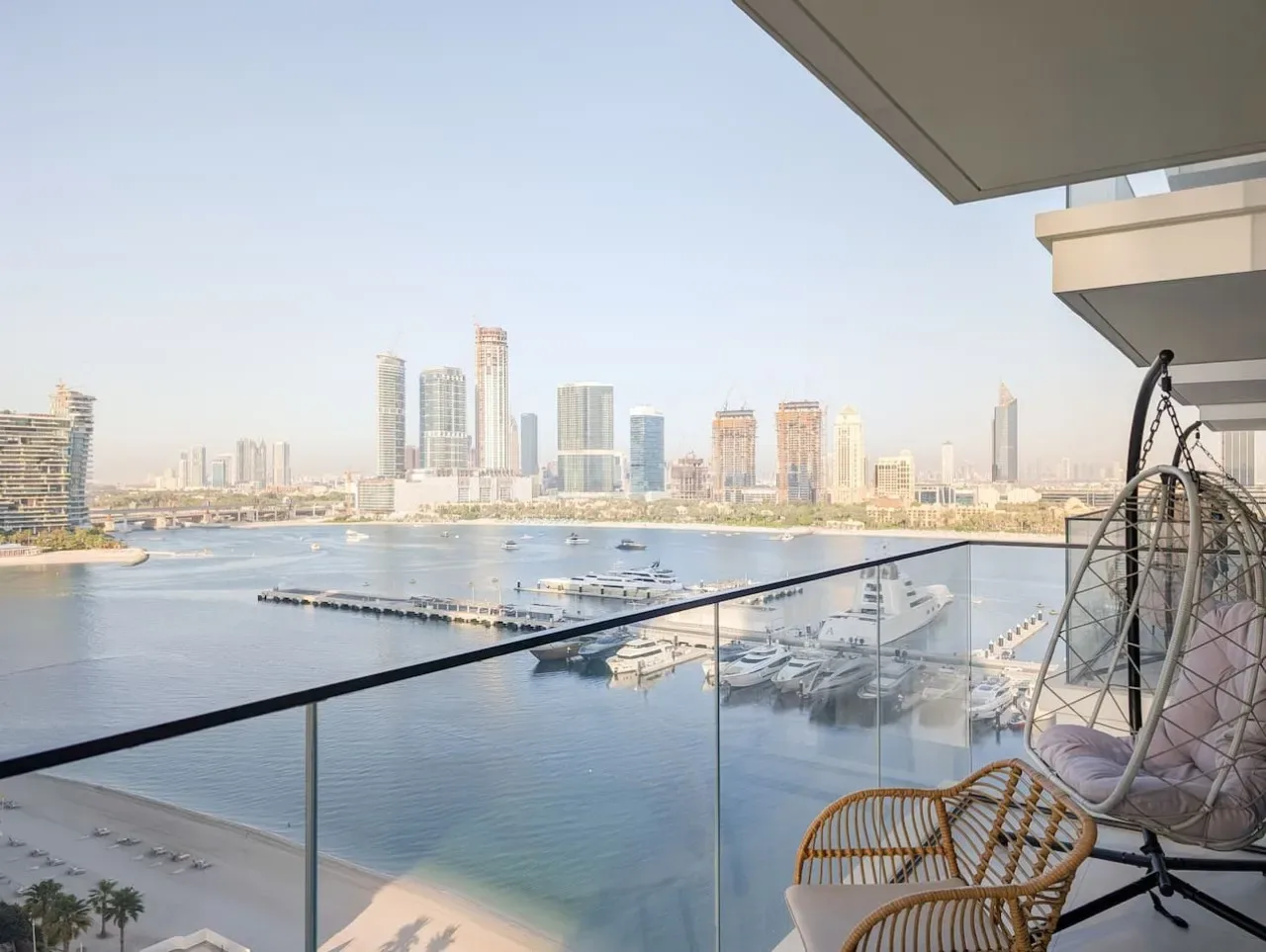 Un balcón da a una zona costera con barcos y un horizonte urbano a lo lejos.