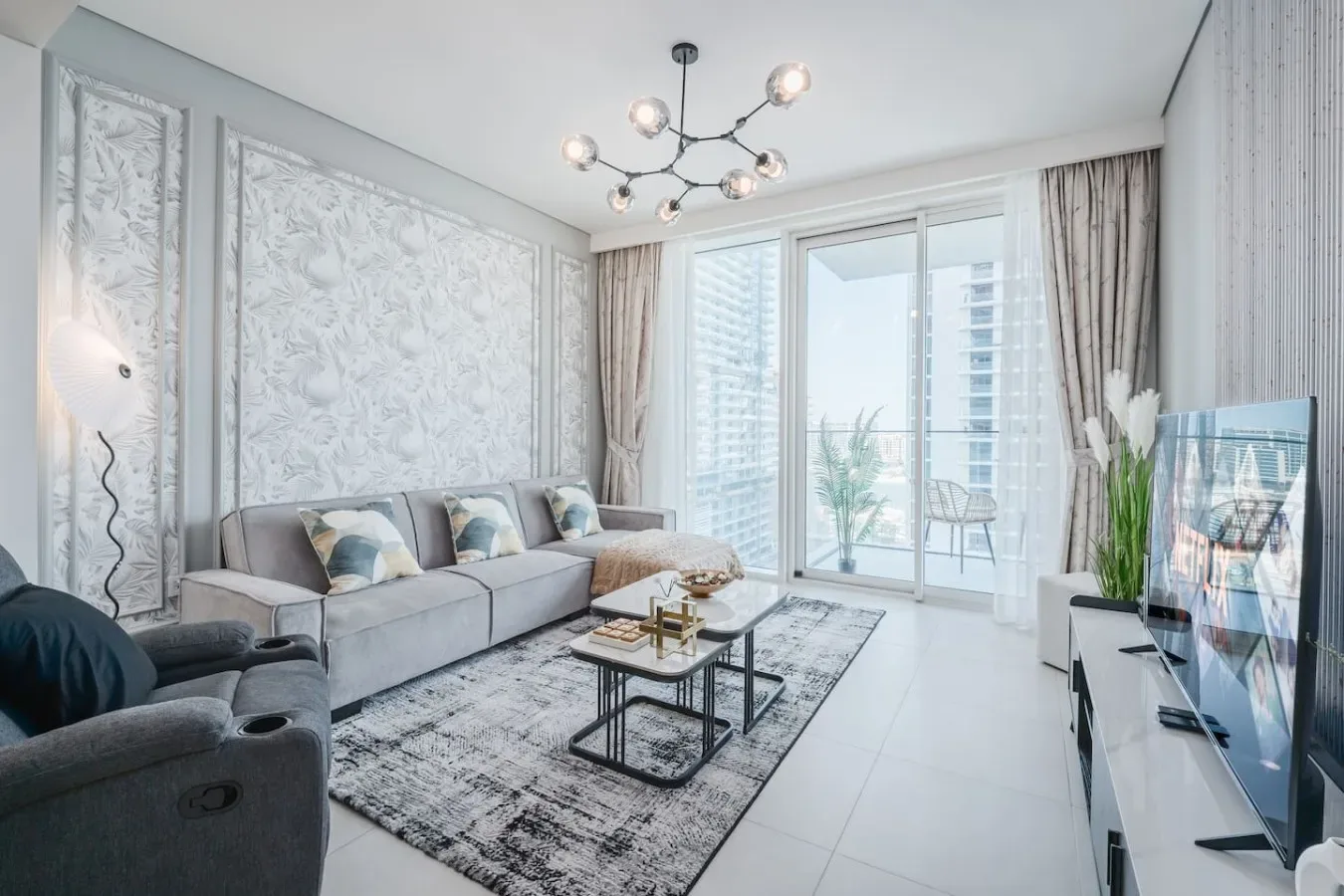 Una sala luminosa con asientos, una mesa de centro y grandes ventanas con vista a un balcón.