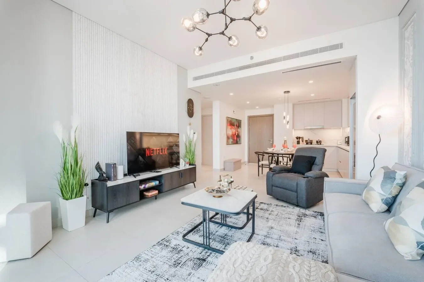 Una luminosa sala de estar moderna se abre a un comedor y una cocina.